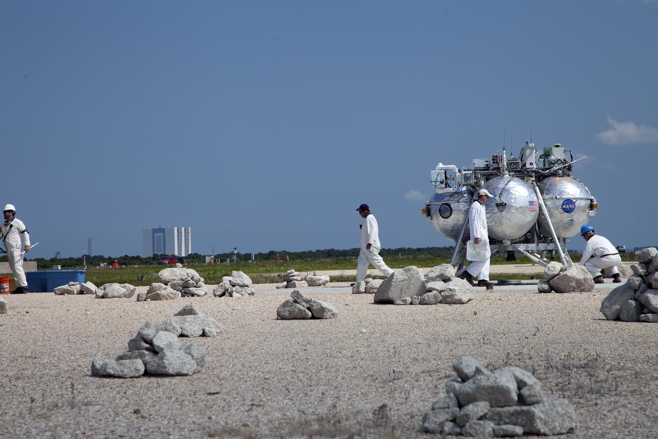 CAPE CANAVERAL, Fla. – Technicians and engineers prepare NASA's Project Morpheus prototype lander for a free flight test from a new launch pad at the north end of the Shuttle Landing Facility at NASA's Kennedy Space Center in Florida. The 98-second test began at 3:20 p.m. EDT with the Morpheus lander launching from the ground over a flame trench and ascending more than 800 feet at a peak speed of 36 mph. The vehicle, with its recently installed autonomous landing and hazard avoidance technology ALHAT sensors, surveyed the hazard field to determine safe landing sites. Morpheus then flew forward and downward covering approximately 1300 feet while performing a 78-foot divert to simulate a hazard avoidance maneuver. The lander then descended and landed on a dedicated pad inside the autonomous landing and hazard avoidance technology hazard field. Project Morpheus tests NASA’s ALHAT and an engine that runs on liquid oxygen and methane, which are green propellants. These new capabilities could be used in future efforts to deliver cargo to planetary surfaces. The landing facility provides the lander with the kind of field necessary for realistic testing, complete with rocks, craters and hazards to avoid. Morpheus’ ALHAT payload allows it to navigate to clear landing sites amidst rocks, craters and other hazards during its descent. Project Morpheus is being managed under the Advanced Exploration Systems, or AES, Division in NASA’s Human Exploration and Operations Mission Directorate. The efforts in AES pioneer new approaches for rapidly developing prototype systems, demonstrating key capabilities and validating operational concepts for future human missions beyond Earth orbit. For more information on Project Morpheus, visit http://morpheuslander.jsc.nasa.gov/. Photo credit: NASA/Daniel Casper