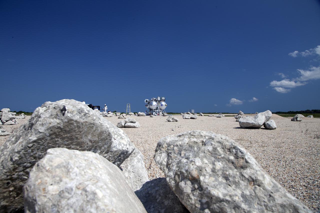 CAPE CANAVERAL, Fla. – Technicians and engineers prepare NASA's Project Morpheus prototype lander for a free flight test from a new launch pad at the north end of the Shuttle Landing Facility at NASA's Kennedy Space Center in Florida. The 98-second test began at 3:20 p.m. EDT with the Morpheus lander launching from the ground over a flame trench and ascending more than 800 feet at a peak speed of 36 mph. The vehicle, with its recently installed autonomous landing and hazard avoidance technology ALHAT sensors, surveyed the hazard field to determine safe landing sites. Morpheus then flew forward and downward covering approximately 1300 feet while performing a 78-foot divert to simulate a hazard avoidance maneuver. The lander then descended and landed on a dedicated pad inside the autonomous landing and hazard avoidance technology hazard field. Project Morpheus tests NASA’s ALHAT and an engine that runs on liquid oxygen and methane, which are green propellants. These new capabilities could be used in future efforts to deliver cargo to planetary surfaces. The landing facility provides the lander with the kind of field necessary for realistic testing, complete with rocks, craters and hazards to avoid. Morpheus’ ALHAT payload allows it to navigate to clear landing sites amidst rocks, craters and other hazards during its descent. Project Morpheus is being managed under the Advanced Exploration Systems, or AES, Division in NASA’s Human Exploration and Operations Mission Directorate. The efforts in AES pioneer new approaches for rapidly developing prototype systems, demonstrating key capabilities and validating operational concepts for future human missions beyond Earth orbit. For more information on Project Morpheus, visit http://morpheuslander.jsc.nasa.gov/. Photo credit: NASA/Daniel Casper