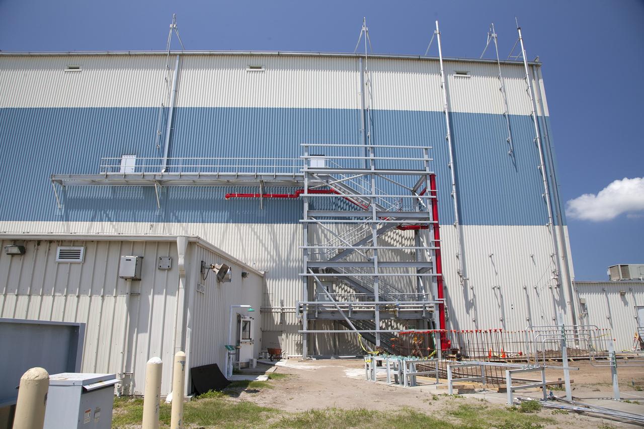 CAPE CANAVERAL, Fla. – Modifications continue on the Multi-Payload Processing Facility, or MPPF, at NASA's Kennedy Space Center in Florida. A new emergency egress stairway has been constructed and a steel structure has been built around it so that walls can be added. The red pipes are the recently-installed fire deluge system. The gray pipes are the hazardous gas venting system.    Kennedy's Center Operations Directorate is overseeing upgrades to the MPPF for the Ground Systems Development and Operations Program. The extensive upgrades and modernizations will support processing of Orion spacecraft for NASA's exploration missions. The 19,647-square-foot building, originally constructed in 1995, primarily will be used for Orion hypergolic fueling, ammonia servicing and high-pressure gas servicing and checkout before being transported to the Vehicle Assembly Building for integration with the Space Launch System. Photo credit: NASA/Daniel Casper