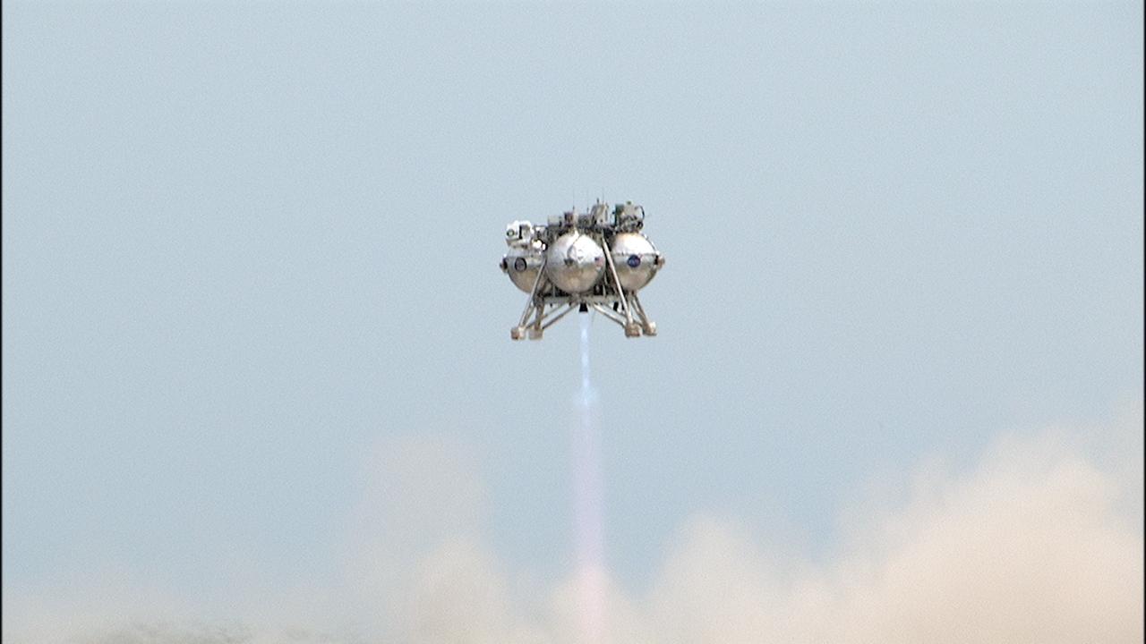 CAPE CANAVERAL, Fla. – NASA's Project Morpheus prototype lander soars high after lifting off on a free-flight test from a new launch pad at the north end of the Shuttle Landing Facility at NASA's Kennedy Space Center in Florida. The 98-second test began at 1:57 p.m. EDT with the Morpheus lander launching from the ground over a flame trench and ascending more than 800 feet at a peak speed of 36 mph. The vehicle, with its recently installed autonomous landing and hazard avoidance technology, or ALHAT, sensors surveyed the hazard field to determine safe landing sites. Morpheus then flew forward and downward covering approximately 1300 feet while performing a 78-foot divert to simulate a hazard avoidance maneuver. The lander descended and landed on a dedicated pad inside the ALHAT hazard field. Project Morpheus tests NASA’s ALHAT and an engine that runs on liquid oxygen and methane, which are green propellants. These new capabilities could be used in future efforts to deliver cargo to planetary surfaces.    The landing facility provides the lander with the kind of field necessary for realistic testing, complete with rocks, craters and hazards to avoid. Morpheus’ ALHAT payload allows it to navigate to clear landing sites amidst rocks, craters and other hazards during its descent. Project Morpheus is being managed under the Advanced Exploration Systems, or AES, Division in NASA’s Human Exploration and Operations Mission Directorate. The efforts in AES pioneer new approaches for rapidly developing prototype systems, demonstrating key capabilities and validating operational concepts for future human missions beyond Earth orbit. For more information on Project Morpheus, visit http://morpheuslander.jsc.nasa.gov/.  Photo credit: NASA/Frankie Martin