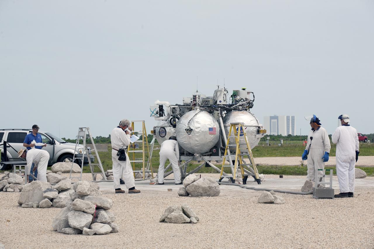 CAPE CANAVERAL, Fla. – Engineers and technicians check NASA's Project Morpheus prototype lander after it touched down on a dedicated landing pad inside the autonomous landing and hazard avoidance technology, or ALHAT, hazard field at the north end of the Shuttle Landing Facility at NASA's Kennedy Space Center in Florida. Morpheus launched on a free-flight test from a new launch pad at the north end of the landing facility. The 98-second test began at 1:57 p.m. EDT with the Morpheus lander launching from the ground over a flame trench and ascending more than 800 feet at a peak speed of 36 mph. The vehicle, with its recently installed ALHAT sensors, surveyed the hazard field to determine safe landing sites. Morpheus then flew forward and downward covering approximately 1300 feet while performing a 78-foot divert to simulate a hazard avoidance maneuver before landing on the dedicated pad inside the ALHAT hazard field. Project Morpheus tests NASA’s ALHAT and an engine that runs on liquid oxygen and methane, which are green propellants. These new capabilities could be used in future efforts to deliver cargo to planetary surfaces.    The landing facility provides the lander with the kind of field necessary for realistic testing, complete with rocks, craters and hazards to avoid. Morpheus’ ALHAT payload allows it to navigate to clear landing sites amidst rocks, craters and other hazards during its descent. Project Morpheus is being managed under the Advanced Exploration Systems, or AES, Division in NASA’s Human Exploration and Operations Mission Directorate. The efforts in AES pioneer new approaches for rapidly developing prototype systems, demonstrating key capabilities and validating operational concepts for future human missions beyond Earth orbit. For more information on Project Morpheus, visit http://morpheuslander.jsc.nasa.gov/.  Photo credit: NASA/Kim Shiflett