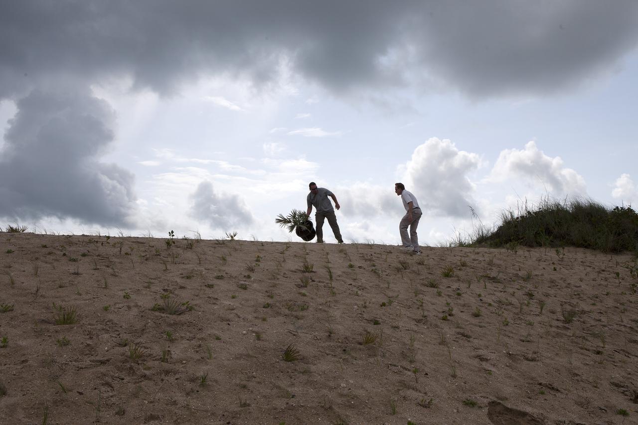 CAPE CANAVERAL, Fla. -- At the Kennedy Space Center in Florida, Don Dankert, a biological scientist in the NASA Environmental Management Branch of Center Operations, left, and Glenn Semmel, chief of the Environmental Management Branch of Center Operations retrieve the final shrub that is among 180,000 planted on a new 1.2-mile stretch of shoreline near Launch Pads 39A and B.      Constant pounding from tropical storms, such as Hurricane Sandy in October of 2012, other weather systems and higher than usual tides, destroyed sand dunes protecting infrastructure at the spaceport. Photo credit: NASA/Dan Casper