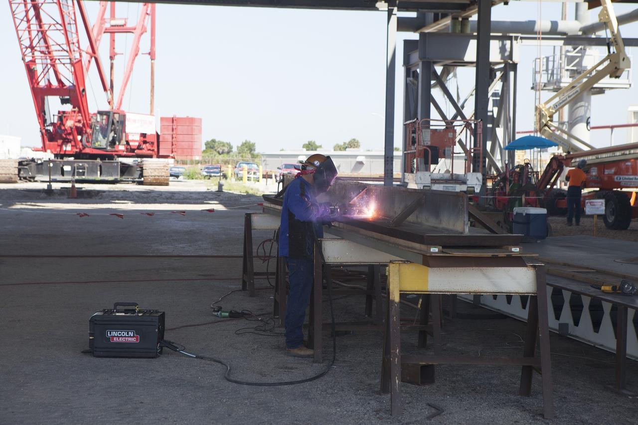 CAPE CANAVERAL, Fla. – Modifications continue on the Mobile Launcher, or ML, at the Mobile Launcher Park Site at NASA’s Kennedy Space Center in Florida. A construction worker welds a section of a steel beam. The ML is being modified and strengthened to accommodate the weight, size and thrust at launch of NASA's Space Launch System and Orion spacecraft.    In 2013, the agency awarded a contract to J.P. Donovan Construction Inc. of Rockledge, Fla., to modify the ML, which is one of the key elements of ground support equipment that is being upgraded by the Ground Systems Development and Operations Program office at Kennedy. The existing 24-foot exhaust hole is being enlarged and strengthened for the larger, heavier SLS rocket. The ML will carry the SLS rocket and Orion spacecraft to Launch Pad 39B for its first mission, Exploration Mission-1, in 2017. Photo credit: NASA/Daniel Casper