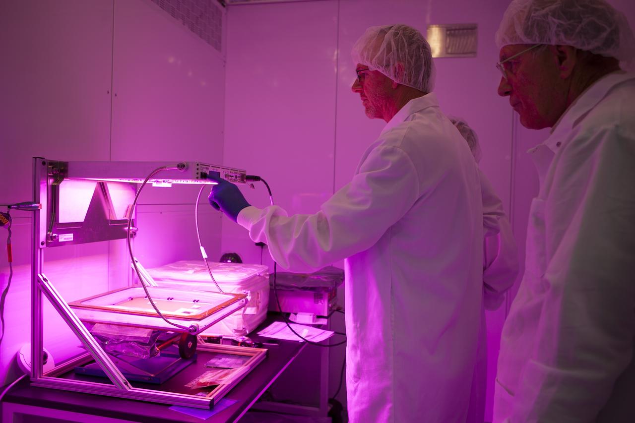 CAPE CANAVERAL, Fla. – Researchers activate the red, blue and green LED lights on the Veggie plant growth system inside a control chamber at the Space Station Processing Facility at NASA's Kennedy Space Center in Florida. From left, are Jim Smodell, a technician with SGT, and Chuck Spern, lead project engineer, with QinetiQ North America. The growth chamber will be used as a control unit and procedures will be followed identical to those being performed on Veggie and the Veg-01 experiment on the International Space Station by Expedition 39 flight engineer and NASA astronaut Steve Swanson.    Veggie and Veg-01 were delivered to the space station aboard the SpaceX-3 mission. Veggie is the first fresh food production system delivered to the station. Six plant pillows, each containing outredgeous red romaine lettuce seeds and a root mat were inserted into Veggie. The plant chamber's red, blue and green LED lights were activated. The plant growth will be monitored for 28 days. At the end of the cycle, the plants will be carefully harvested, frozen and stored for return to Earth. Photo credit: NASA/Dimitri Gerondidakis