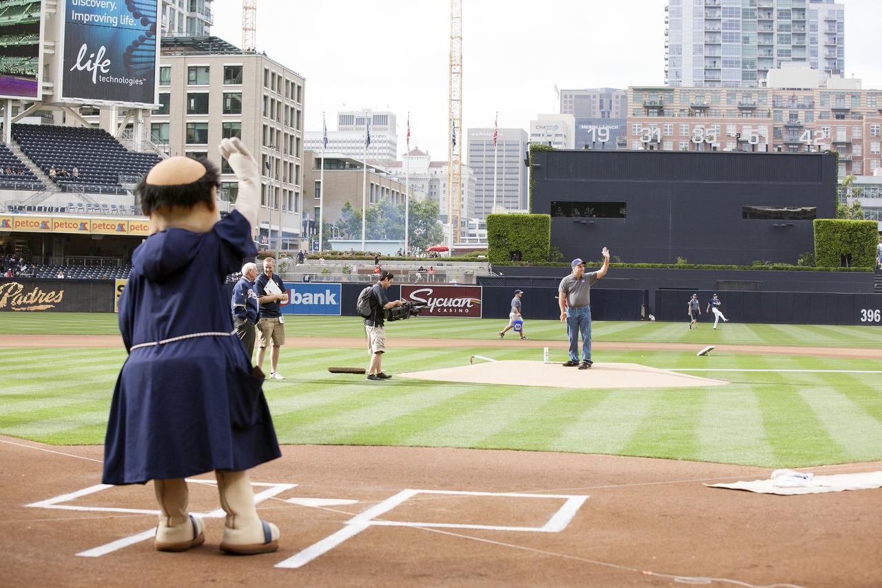 CAPE CANAVERAL, Fla. – Doug Lenhardt, Kennedy Space Center's Exploration Flight Test-1, or EFT-1, mission integration manager, and the San Diego Padres mascot wave at the crowds at Petco Field in San Diego, California before the start of the baseball game. The Orion boilerplate test vehicle is on display in the stadium. The boilerplate test vehicle is being prepared for an EFT-1 pre-transportation test. The Ground Systems Development and Operations Program will run the test at the U.S. Naval Base San Diego to simulate retrieval and transportation procedures for Orion after it splashes down in the ocean and is retrieved for return to land and ground transportation back to Kennedy Space Center in Florida.    Orion is the exploration spacecraft designed to carry astronauts to destinations not yet explored by humans, including an asteroid and Mars. It will have emergency abort capability, sustain the crew during space travel and provide safe re-entry from deep space return velocities. The first unpiloted test flight of the Orion is scheduled to launch later this year atop a Delta IV rocket and in 2017 on NASA’s Space Launch System rocket. For more information, visit http://www.nasa.gov/orion. Photo credit: NASA/Kim Shiflett