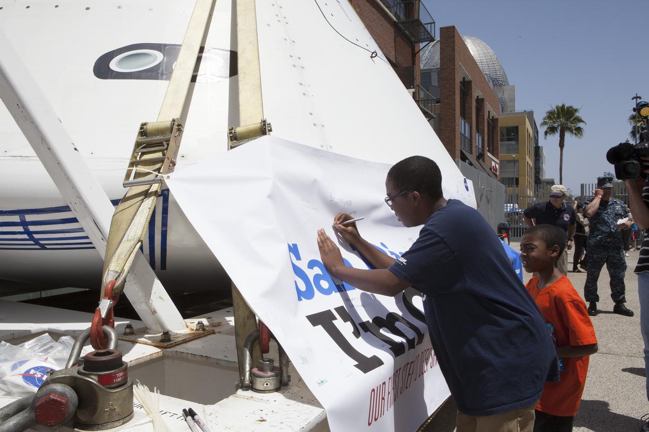 CAPE CANAVERAL, Fla. – Fans sign the banner surrounding NASA's Orion boilerplate test vehicle on display at Petco Park in San Diego, California, before the start of a San Diego Padres' baseball game. The boilerplate test vehicle is being prepared for an Exploration Flight Test-1, or EFT-1, pre-transportation test. The Ground Systems Development and Operations Program will run the test at the U.S. Naval Base San Diego to simulate retrieval and transportation procedures for Orion after it splashes down in the ocean and is retrieved for return to land and ground transportation back to Kennedy Space Center in Florida.     Orion is the exploration spacecraft designed to carry astronauts to destinations not yet explored by humans, including an asteroid and Mars. It will have emergency abort capability, sustain the crew during space travel and provide safe re-entry from deep space return velocities. The first unpiloted test flight of the Orion is scheduled to launch later this year atop a Delta IV rocket and in 2017 on NASA’s Space Launch System rocket. For more information, visit http://www.nasa.gov/orion. Photo credit: NASA/Kim Shiflett