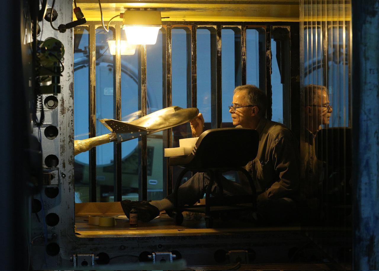 HAMPTON, Va. – NASA technician Ricky Hall works inside the Unitary Plan Wind Tunnel at NASA's Langley Research Center in Virginia to affix grains of sand to a precise scale model of the Dream Chaser spacecraft. Sierra Nevada Corporation is developing the Dream Chaser in partnership with NASA's Commercial Crew Program. The sand creates turbulence at key points to simulate the conditions the real spacecraft will encounter during its return to Earth. The data gathered from the wind tunnel was used to further test the design through the company's Commercial Crew Integrated Capability agreement with NASA. Photo credit: NASA/ David C. Bowman