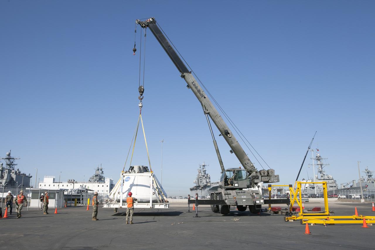 SAN DIEGO, Calif. – A crane lowers the Orion boilerplate test vehicle onto the ground at a warehouse at the Naval Base San Diego in California. The test vehicle is attached to the BTA handling fixture. The Ground Systems Development and Operations Program, Lockheed Martin and the U.S. Navy are evaluating the hardware and processes for preparing the Orion crew module for Exploration Flight Test-1, or EFT-1, for overland transport from the naval base to NASA's Kennedy Space Center in Florida. Orion is the exploration spacecraft designed to carry astronauts to destinations not yet explored by humans, including an asteroid and Mars. It will have emergency abort capability, sustain the crew during space travel and provide safe re-entry from deep space return velocities. The first unpiloted test flight of the Orion is scheduled to launch later this year atop a Delta IV rocket from Cape Canaveral Air Force Station in Florida to an altitude of 3,600 miles above the Earth's surface. The two-orbit, four-hour flight test will help engineers evaluate the systems critical to crew safety including the heat shield, parachute system and launch abort system. For more information, visit http://www.nasa.gov/orion. Photo credit: NASA/Kim Shiflett