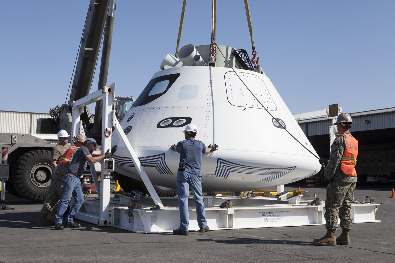 SAN DIEGO, Calif. – U.S. Navy and Jacobs/TOSC workers help detach the Orion boilerplate test vehicle from the BTA handling fixture as a crane begins to lift it away at a warehouse at the Naval Base San Diego in California. The Ground Systems Development and Operations Program, Lockheed Martin and U.S. Navy are evaluating the hardware and processes for preparing the Orion crew module for Exploration Flight Test-1, or EFT-1, for overland transport from the naval base to NASA's Kennedy Space Center in Florida.    Orion is the exploration spacecraft designed to carry astronauts to destinations not yet explored by humans, including an asteroid and Mars. It will have emergency abort capability, sustain the crew during space travel and provide safe re-entry from deep space return velocities. The first unpiloted test flight of the Orion is scheduled to launch later this year atop a Delta IV rocket from Cape Canaveral Air Force Station in Florida to an altitude of 3,600 miles above the Earth's surface. The two-orbit, four-hour flight test will help engineers evaluate the systems critical to crew safety including the heat shield, parachute system and launch abort system. For more information, visit http://www.nasa.gov/orion. Photo credit: NASA/Kim Shiflett