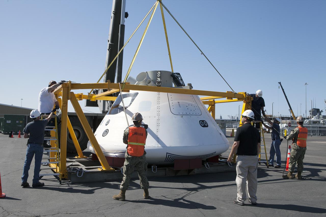 SAN DIEGO, Calif. – A crane lowers the top fixture of the crew module recovery cradle onto the Orion boilerplate test vehicle at a warehouse at the Naval Base San Diego in California. The Ground Systems Development and Operations Program, Lockheed Martin and U.S. Navy are evaluating the hardware and processes for preparing the Orion crew module for Exploration Flight Test-1, or EFT-1, for overland transport from the naval base to NASA's Kennedy Space Center in Florida.    Orion is the exploration spacecraft designed to carry astronauts to destinations not yet explored by humans, including an asteroid and Mars. It will have emergency abort capability, sustain the crew during space travel and provide safe re-entry from deep space return velocities. The first unpiloted test flight of the Orion is scheduled to launch later this year atop a Delta IV rocket from Cape Canaveral Air Force Station in Florida to an altitude of 3,600 miles above the Earth's surface. The two-orbit, four-hour flight test will help engineers evaluate the systems critical to crew safety including the heat shield, parachute system and launch abort system. For more information, visit http://www.nasa.gov/orion. Photo credit: NASA/Kim Shiflett