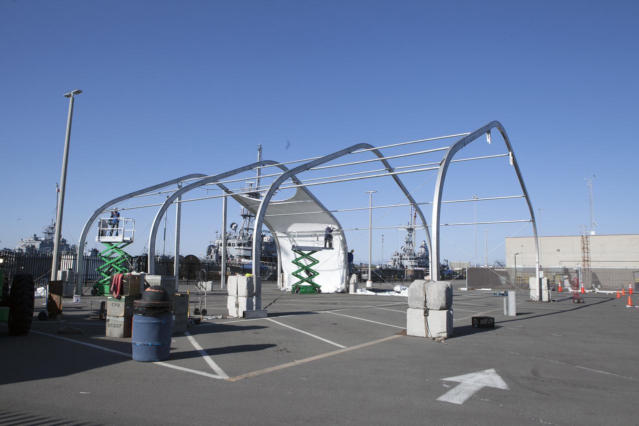 SAN DIEGO, Calif. – Workers on scissor lifts build up a protective structure at the Mole Pier at the Naval Base San Diego in California for the Orion boilerplate test vehicle. The Ground Systems Development and Operations Program, Lockheed Martin and U.S. Navy are evaluating the hardware and processes for preparing the Orion crew module for Exploration Flight Test-1, or EFT-1, for overland transport from the naval base to NASA's Kennedy Space Center in Florida.    Orion is the exploration spacecraft designed to carry astronauts to destinations not yet explored by humans, including an asteroid and Mars. It will have emergency abort capability, sustain the crew during space travel and provide safe re-entry from deep space return velocities. The first unpiloted test flight of the Orion is scheduled to launch later this year atop a Delta IV rocket from Cape Canaveral Air Force Station in Florida to an altitude of 3,600 miles above the Earth's surface. The two-orbit, four-hour flight test will help engineers evaluate the systems critical to crew safety including the heat shield, parachute system and launch abort system. For more information, visit http://www.nasa.gov/orion. Photo credit: NASA/Kim Shiflett