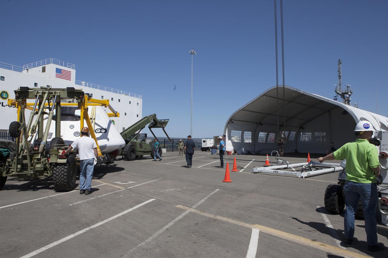 SAN DIEGO, Calif. – Workers prepare to move the Orion boilerplate test vehicle into a protective structure at the Mole Pier at the Naval Base San Diego in California for a simulated fit check of the hatch cover. The test vehicle is attached to the crew module recovery cradle. The Ground Systems Development and Operations Program, Lockheed Martin and the U.S. Navy are evaluating the hardware and processes for preparing the Orion crew module for Exploration Flight Test-1, or EFT-1, for overland transport from the naval base to NASA's Kennedy Space Center in Florida.     Orion is the exploration spacecraft designed to carry astronauts to destinations not yet explored by humans, including an asteroid and Mars. It will have emergency abort capability, sustain the crew during space travel and provide safe re-entry from deep space return velocities. The first unpiloted test flight of the Orion is scheduled to launch later this year atop a Delta IV rocket from Cape Canaveral Air Force Station in Florida to an altitude of 3,600 miles above the Earth's surface. The two-orbit, four-hour flight test will help engineers evaluate the systems critical to crew safety including the heat shield, parachute system and launch abort system. For more information, visit http://www.nasa.gov/orion. Photo credit: NASA/Kim Shiflett
