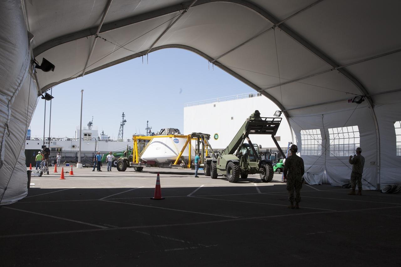 SAN DIEGO, Calif. – The Orion boilerplate test vehicle is being moved into a protective structure at the Mole Pier at the Naval Base San Diego in California for a simulated fit check of the hatch cover. The test vehicle is attached to the crew module recovery cradle. The Ground Systems Development and Operations Program, Lockheed Martin and the U.S. Navy are evaluating the hardware and processes for preparing the Orion crew module for Exploration Flight Test-1, or EFT-1, for overland transport from the naval base to NASA's Kennedy Space Center in Florida.    Orion is the exploration spacecraft designed to carry astronauts to destinations not yet explored by humans, including an asteroid and Mars. It will have emergency abort capability, sustain the crew during space travel and provide safe re-entry from deep space return velocities. The first unpiloted test flight of the Orion is scheduled to launch later this year atop a Delta IV rocket from Cape Canaveral Air Force Station in Florida to an altitude of 3,600 miles above the Earth's surface. The two-orbit, four-hour flight test will help engineers evaluate the systems critical to crew safety including the heat shield, parachute system and launch abort system. For more information, visit http://www.nasa.gov/orion. Photo credit: NASA/Kim Shiflett