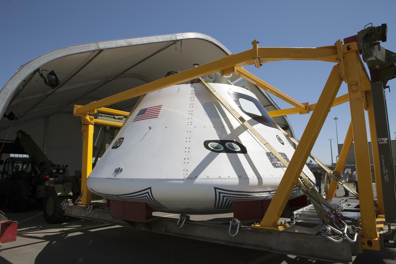 SAN DIEGO, Calif. – The Orion boilerplate test vehicle is being moved into a protective structure at the Mole Pier at the Naval Base San Diego in California for a simulated fit check of the hatch cover. The test vehicle is attached to the crew module recovery cradle. The Ground Systems Development and Operations Program, Lockheed Martin and the U.S. Navy are evaluating the hardware and processes for preparing the Orion crew module for Exploration Flight Test-1, or EFT-1, for overland transport from the naval base to NASA's Kennedy Space Center in Florida.    Orion is the exploration spacecraft designed to carry astronauts to destinations not yet explored by humans, including an asteroid and Mars. It will have emergency abort capability, sustain the crew during space travel and provide safe re-entry from deep space return velocities. The first unpiloted test flight of the Orion is scheduled to launch later this year atop a Delta IV rocket from Cape Canaveral Air Force Station in Florida to an altitude of 3,600 miles above the Earth's surface. The two-orbit, four-hour flight test will help engineers evaluate the systems critical to crew safety including the heat shield, parachute system and launch abort system. For more information, visit http://www.nasa.gov/orion. Photo credit: NASA/Kim Shiflett