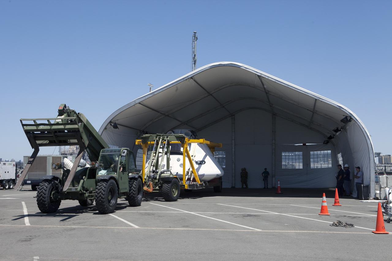 SAN DIEGO, Calif. – The Orion boilerplate test vehicle is being moved into a protective structure at the Mole Pier at the Naval Base San Diego in California for a simulated fit check of the hatch cover. The test vehicle is attached to the crew module recovery cradle. The Ground Systems Development and Operations Program, Lockheed Martin and the U.S. Navy are evaluating the hardware and processes for preparing the Orion crew module for Exploration Flight Test-1, or EFT-1, for overland transport from the naval base to NASA's Kennedy Space Center in Florida.    Orion is the exploration spacecraft designed to carry astronauts to destinations not yet explored by humans, including an asteroid and Mars. It will have emergency abort capability, sustain the crew during space travel and provide safe re-entry from deep space return velocities. The first unpiloted test flight of the Orion is scheduled to launch later this year atop a Delta IV rocket from Cape Canaveral Air Force Station in Florida to an altitude of 3,600 miles above the Earth's surface. The two-orbit, four-hour flight test will help engineers evaluate the systems critical to crew safety including the heat shield, parachute system and launch abort system. For more information, visit http://www.nasa.gov/orion. Photo credit: NASA/Kim Shiflett