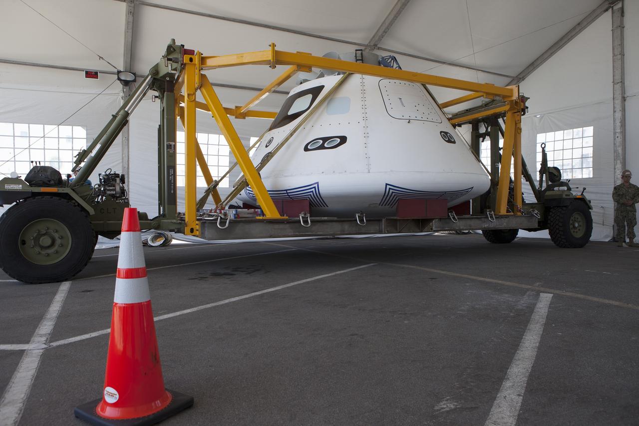 SAN DIEGO, Calif. – The Orion boilerplate test vehicle has been moved into a protective structure at the Mole Pier at the Naval Base San Diego in California for a simulated fit check of the hatch cover. The test vehicle is attached to the crew module recovery cradle. The Ground Systems Development and Operations Program, Lockheed Martin and the U.S. Navy are evaluating the hardware and processes for preparing the Orion crew module for Exploration Flight Test-1, or EFT-1, for overland transport from the naval base to NASA's Kennedy Space Center in Florida.    Orion is the exploration spacecraft designed to carry astronauts to destinations not yet explored by humans, including an asteroid and Mars. It will have emergency abort capability, sustain the crew during space travel and provide safe re-entry from deep space return velocities. The first unpiloted test flight of the Orion is scheduled to launch later this year atop a Delta IV rocket from Cape Canaveral Air Force Station in Florida to an altitude of 3,600 miles above the Earth's surface. The two-orbit, four-hour flight test will help engineers evaluate the systems critical to crew safety including the heat shield, parachute system and launch abort system. For more information, visit http://www.nasa.gov/orion. Photo credit: NASA/Kim Shiflett