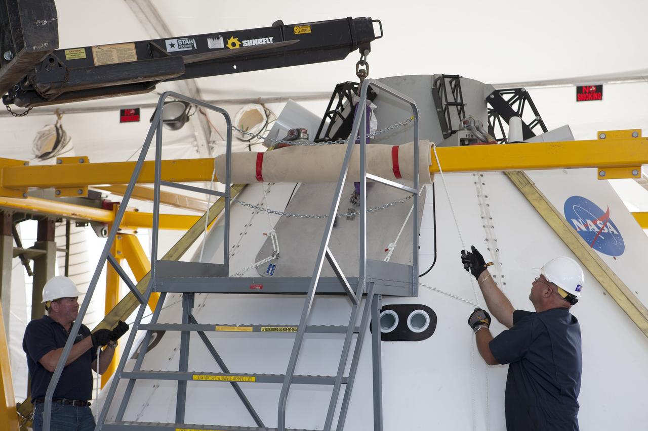 SAN DIEGO, Calif. – Inside a protective structure at the Mole Pier at the Naval Base San Diego in California, workers prepare for a simulated fit check of the hatch cover on the Orion boilerplate test vehicle. The test vehicle is secured on the crew module recovery cradle. The Ground Systems Development and Operations Program, Lockheed Martin and the U.S. Navy are evaluating the hardware and processes for preparing the Orion crew module for Exploration Flight Test-1, or EFT-1, for overland transport from the naval base to NASA's Kennedy Space Center in Florida.    Orion is the exploration spacecraft designed to carry astronauts to destinations not yet explored by humans, including an asteroid and Mars. It will have emergency abort capability, sustain the crew during space travel and provide safe re-entry from deep space return velocities. The first unpiloted test flight of the Orion is scheduled to launch later this year atop a Delta IV rocket from Cape Canaveral Air Force Station in Florida to an altitude of 3,600 miles above the Earth's surface. The two-orbit, four-hour flight test will help engineers evaluate the systems critical to crew safety including the heat shield, parachute system and launch abort system. For more information, visit http://www.nasa.gov/orion. Photo credit: NASA/Kim Shiflett