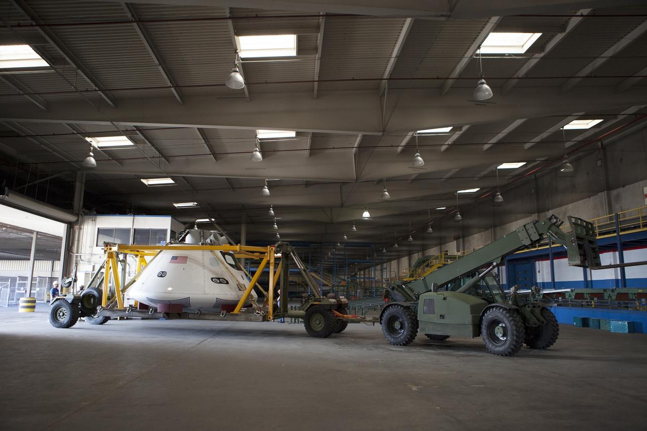 SAN DIEGO, Calif. – The Orion boilerplate test vehicle has been moved to a warehouse at Naval Base San Diego in California from the Mole Pier at the naval base. The test vehicle is attached to the crew module recovery cradle. The Ground Systems Development and Operations Program, Lockheed Martin and the U.S. Navy are evaluating the hardware and processes for preparing the Orion crew module for Exploration Flight Test-1, or EFT-1, for overland transport from the naval base to NASA's Kennedy Space Center in Florida.    Orion is the exploration spacecraft designed to carry astronauts to destinations not yet explored by humans, including an asteroid and Mars. It will have emergency abort capability, sustain the crew during space travel and provide safe re-entry from deep space return velocities. The first unpiloted test flight of the Orion is scheduled to launch later this year atop a Delta IV rocket from Cape Canaveral Air Force Station in Florida to an altitude of 3,600 miles above the Earth's surface. The two-orbit, four-hour flight test will help engineers evaluate the systems critical to crew safety including the heat shield, parachute system and launch abort system. For more information, visit http://www.nasa.gov/orion. Photo credit: NASA/Kim Shiflett