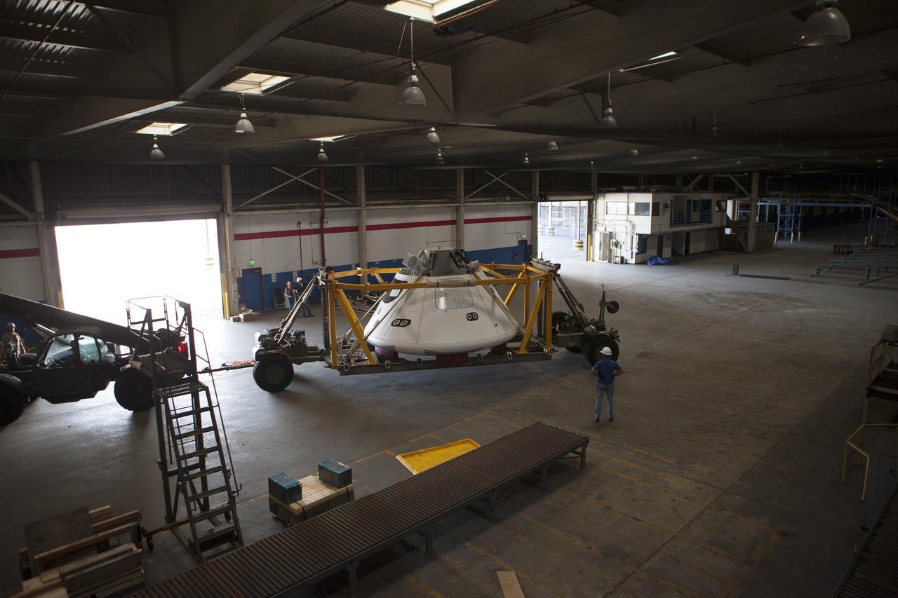 SAN DIEGO, Calif. – The Orion boilerplate test vehicle has been moved to a warehouse at Naval Base San Diego in California from the Mole Pier at the naval base. The test vehicle is attached to the crew module recovery cradle. The Ground Systems Development and Operations Program, Lockheed Martin and the U.S. Navy are evaluating the hardware and processes for preparing the Orion crew module for Exploration Flight Test-1, or EFT-1, for overland transport from the naval base to NASA's Kennedy Space Center in Florida.    Orion is the exploration spacecraft designed to carry astronauts to destinations not yet explored by humans, including an asteroid and Mars. It will have emergency abort capability, sustain the crew during space travel and provide safe re-entry from deep space return velocities. The first unpiloted test flight of the Orion is scheduled to launch later this year atop a Delta IV rocket from Cape Canaveral Air Force Station in Florida to an altitude of 3,600 miles above the Earth's surface. The two-orbit, four-hour flight test will help engineers evaluate the systems critical to crew safety including the heat shield, parachute system and launch abort system. For more information, visit http://www.nasa.gov/orion. Photo credit: NASA/Kim Shiflett