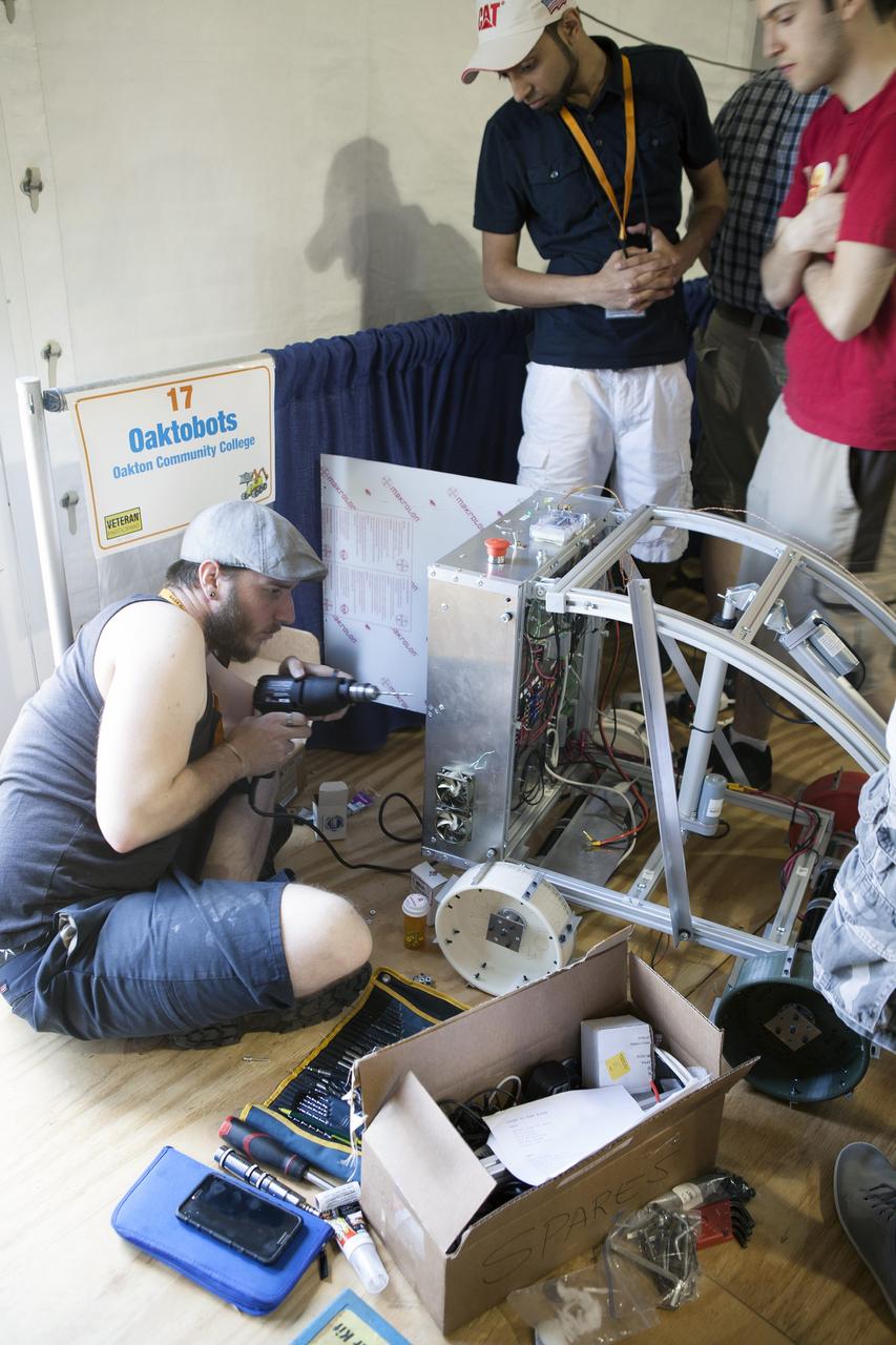 CAPE CANAVERAL, Fla. – Students from Oakton Community College in Illinois prepare their robot for NASA’s Robotics Mining Competition at the Kennedy Space Center Visitor Complex in Florida. More than 35 teams from around the U.S. have designed and built remote-controlled robots for the mining competition.    The competition is a NASA Human Exploration and Operations Mission Directorate project designed to engage and retain students in science, technology, engineering and mathematics, or STEM, fields by expanding opportunities for student research and design. Teams use their remote-controlled robotics to maneuver and dig in a supersized sandbox filled with a crushed material that has characteristics similar to Martian soil. The objective of the challenge is to see which team’s robot can collect and move the most regolith within a specified amount of time. For more information, visit www.nasa.gov/nasarmc. Photo credit: NASA/Ben Smegelsky