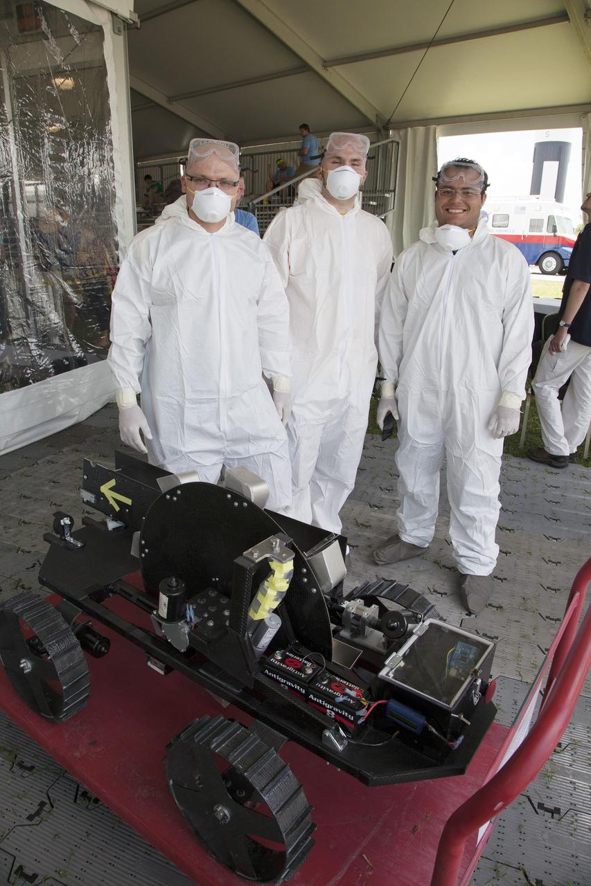 CAPE CANAVERAL, Fla. – College students from Montana State University, dressed in protective suits, prepare their robot for a trial run at NASA’s Robotics Mining Competition at the Kennedy Space Center Visitor Complex in Florida. More than 35 teams from around the U.S. have designed and built remote-controlled robots for the mining competition. The competition is a NASA Human Exploration and Operations Mission Directorate project designed to engage and retain students in science, technology, engineering and mathematics, or STEM, fields by expanding opportunities for student research and design. Teams use their remote-controlled robotics to maneuver and dig in a supersized sandbox filled with a crushed material that has characteristics similar to Martian soil. The objective of the challenge is to see which team’s robot can collect and move the most regolith within a specified amount of time. For more information, visit www.nasa.gov/nasarmc. Photo credit: NASA/Ben Smegelsky