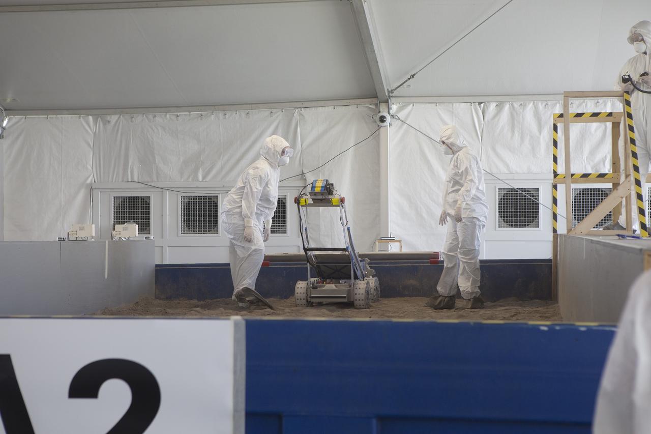 CAPE CANAVERAL, Fla. – College students, dressed in protective suits, monitor a trial run of their robot during NASA’s Robotics Mining Competition at the Kennedy Space Center Visitor Complex in Florida. More than 35 teams from around the U.S. have designed and built remote-controlled robots for the mining competition. The competition is a NASA Human Exploration and Operations Mission Directorate project designed to engage and retain students in science, technology, engineering and mathematics, or STEM, fields by expanding opportunities for student research and design. Teams use their remote-controlled robotics to maneuver and dig in a supersized sandbox filled with a crushed material that has characteristics similar to Martian soil. The objective of the challenge is to see which team’s robot can collect and move the most regolith within a specified amount of time. For more information, visit www.nasa.gov/nasarmc. Photo credit: NASA/Ben Smegelsky