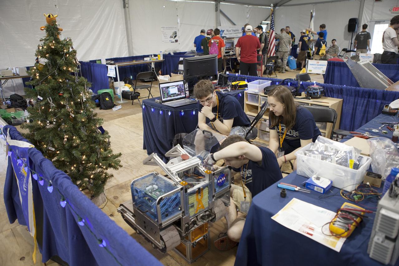 CAPE CANAVERAL, Fla. – College and university teams prepare their robots for NASA’s Robotics Mining Competition at the Kennedy Space Center Visitor Complex in Florida. More than 35 teams from around the U.S. have designed and built remote-controlled robots for the mining competition. The competition is a NASA Human Exploration and Operations Mission Directorate project designed to engage and retain students in science, technology, engineering and mathematics, or STEM, fields by expanding opportunities for student research and design. Teams use their remote-controlled robotics to maneuver and dig in a supersized sandbox filled with a crushed material that has characteristics similar to Martian soil. The objective of the challenge is to see which team’s robot can collect and move the most regolith within a specified amount of time. For more information, visit www.nasa.gov/nasarmc. Photo credit: NASA/Ben Smegelsky