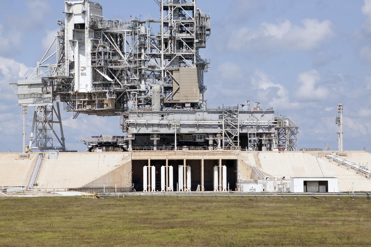 CAPE CANAVERAL, Fla. -- A crawler-transporter rolls under the Mobile Launcher Platform-2, or MLP-2, positioned over the flame trench at Launch Pad 39A at NASA's Kennedy Space Center in Florida. Operations are underway to move the MLP to a nearby park site in Launch Complex 39.      The historic launch pad was the site from which numerous Apollo and space shuttle missions began and is beginning a new mission as a commercial launch site. NASA signed a property agreement with Space Exploration Technologies Corp., or SpaceX, of Hawthorne, California, on April 14 for use and occupancy of the seaside complex along Florida's central east coast. It will serve as a platform for SpaceX to support their commercial launch activities.  For more information on Launch Pad 39A, visit http://www.nasa.gov/centers/kennedy/pdf/167416main_LC39-08.pdf. For learn more about the crawler-transporter, visit http://www.nasa.gov/centers/kennedy/pdf/167402main_crawlertransporters07.pdf. Photo credit: NASA/Kim Shiflett
