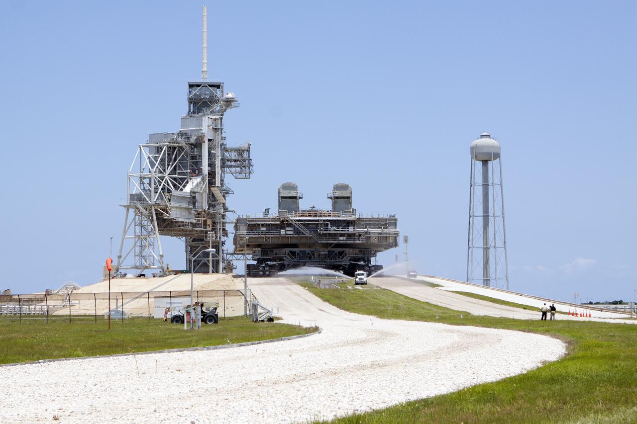 CAPE CANAVERAL, Fla. -- At NASA's Kennedy Space Center in Florida, a truck sprays water along the crawlerway to reduce dust ahead of the crawler-transporter moving Mobile Launcher Platform-2, or MLP-2, from Launch Pad 39A to a nearby park site in Launch Complex 39.      The historic launch pad was the site from which numerous Apollo and space shuttle missions began and is beginning a new mission as a commercial launch site. NASA signed a property agreement with Space Exploration Technologies Corp., or SpaceX, of Hawthorne, California, on April 14 for use and occupancy of the seaside complex along Florida's central east coast. It will serve as a platform for SpaceX to support their commercial launch activities.  For more information on Launch Pad 39A, visit http://www.nasa.gov/centers/kennedy/pdf/167416main_LC39-08.pdf. For learn more about the crawler-transporter, visit http://www.nasa.gov/centers/kennedy/pdf/167402main_crawlertransporters07.pdf. Photo credit: NASA/Kim Shiflett