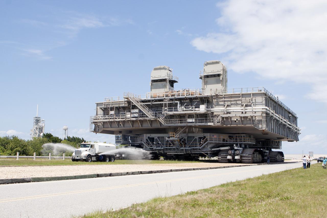 CAPE CANAVERAL, Fla. -- At NASA's Kennedy Space Center in Florida, a truck sprays water along the crawlerway to reduce dust ahead of the crawler-transporter moving Mobile Launcher Platform-2, or MLP-2, from Launch Pad 39A, in the background, to a nearby park site in Launch Complex 39.      The historic launch pad was the site from which numerous Apollo and space shuttle missions began and is beginning a new mission as a commercial launch site. NASA signed a property agreement with Space Exploration Technologies Corp., or SpaceX, of Hawthorne, California, on April 14 for use and occupancy of the seaside complex along Florida's central east coast. It will serve as a platform for SpaceX to support their commercial launch activities.  For more information on Launch Pad 39A, visit http://www.nasa.gov/centers/kennedy/pdf/167416main_LC39-08.pdf. For learn more about the crawler-transporter, visit http://www.nasa.gov/centers/kennedy/pdf/167402main_crawlertransporters07.pdf. Photo credit: NASA/Kim Shiflett