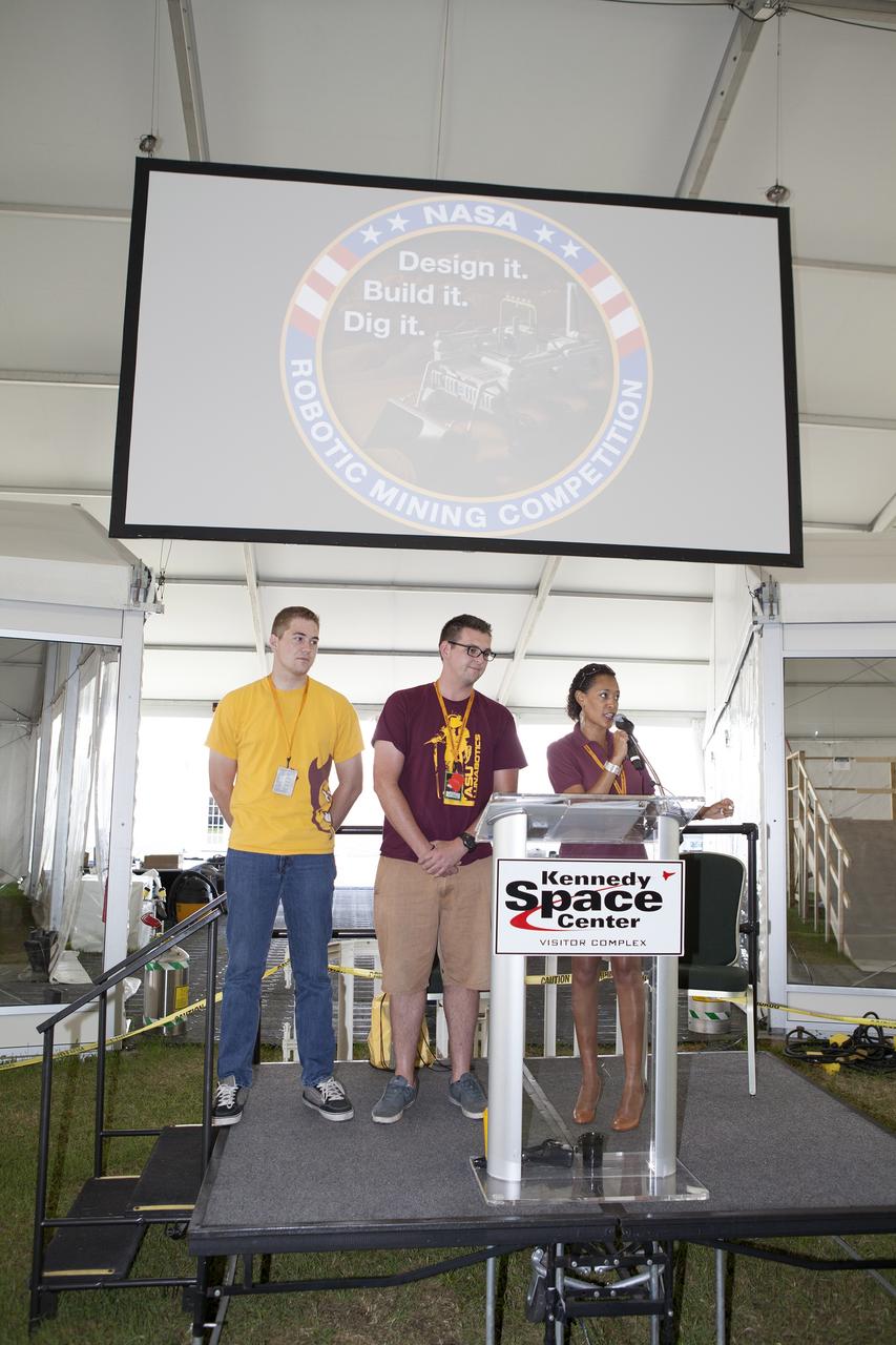 CAPE CANAVERAL, Fla. – During the opening ceremony for NASA's 2014 Robotics Mining Competition at the Kennedy Space Center Visitor Complex in Florida, event emcee Kimberly Land, from NASA's Ames Research Center in Moffett Field, California, asks for a moment of silence for the loss of a team member from Arizona State University. To her left are two team members from the university. More than 35 teams from around the U.S. have designed and built remote-controlled robots for the mining competition.    The competition is a NASA Human Exploration and Operations Mission Directorate project designed to engage and retain students in science, technology, engineering and mathematics, or STEM, fields by expanding opportunities for student research and design. Teams use their remote-controlled robotics to maneuver and dig in a supersized sandbox filled with a crushed material that has characteristics similar to Martian soil. The objective of the challenge is to see which team’s robot can collect and move the most regolith within a specified amount of time. For more information, visit www.nasa.gov/nasarmc. Photo credit: NASA/Frankie Martin