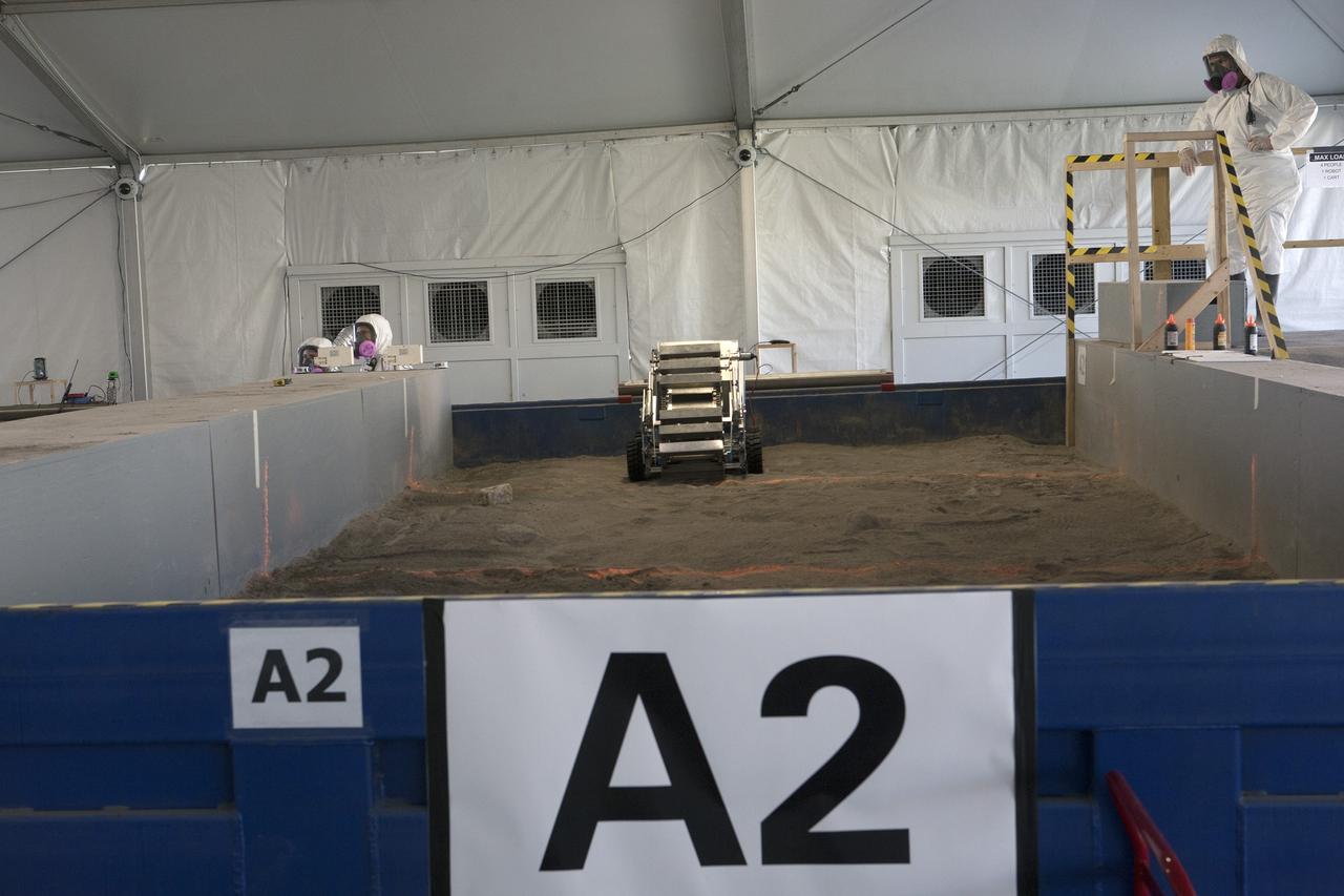 CAPE CANAVERAL, Fla. – Competition judges monitor the progress of a robot digging in the simulated Martian soil in the Caterpillar Mining Arena during NASA’s 2014 Robotic Mining Competition at the Kennedy Space Center Visitor Complex in Florida. More than 35 teams from around the U.S. have designed and built remote-controlled robots for the mining competition. The competition is a NASA Human Exploration and Operations Mission Directorate project designed to engage and retain students in science, technology, engineering and mathematics, or STEM, fields by expanding opportunities for student research and design. Teams use their remote-controlled robotics to maneuver and dig in a supersized sandbox filled with a crushed material that has characteristics similar to Martian soil. The objective of the challenge is to see which team’s robot can collect and move the most regolith within a specified amount of time. For more information, visit www.nasa.gov/nasarmc. Photo credit: NASA/Kim Shiflett