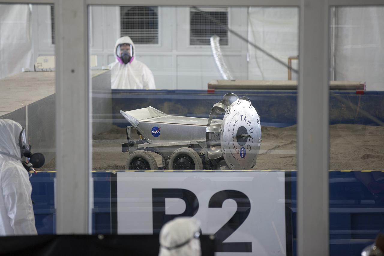 CAPE CANAVERAL, Fla. – Competition judges monitor the progress of a robot digging in the simulated Martian soil in the Caterpillar Mining Arena during NASA’s 2014 Robotic Mining Competition at the Kennedy Space Center Visitor Complex in Florida. More than 35 teams from colleges and universities around the U.S. have designed and built remote-controlled robots for the mining competition. The competition is a NASA Human Exploration and Operations Mission Directorate project designed to engage and retain students in science, technology, engineering and mathematics, or STEM, fields by expanding opportunities for student research and design. Teams use their remote-controlled robotics to maneuver and dig in a supersized sandbox filled with a crushed material that has characteristics similar to Martian soil. The objective of the challenge is to see which team’s robot can collect and move the most regolith within a specified amount of time. For more information, visit www.nasa.gov/nasarmc. Photo credit: NASA/Kim Shiflett