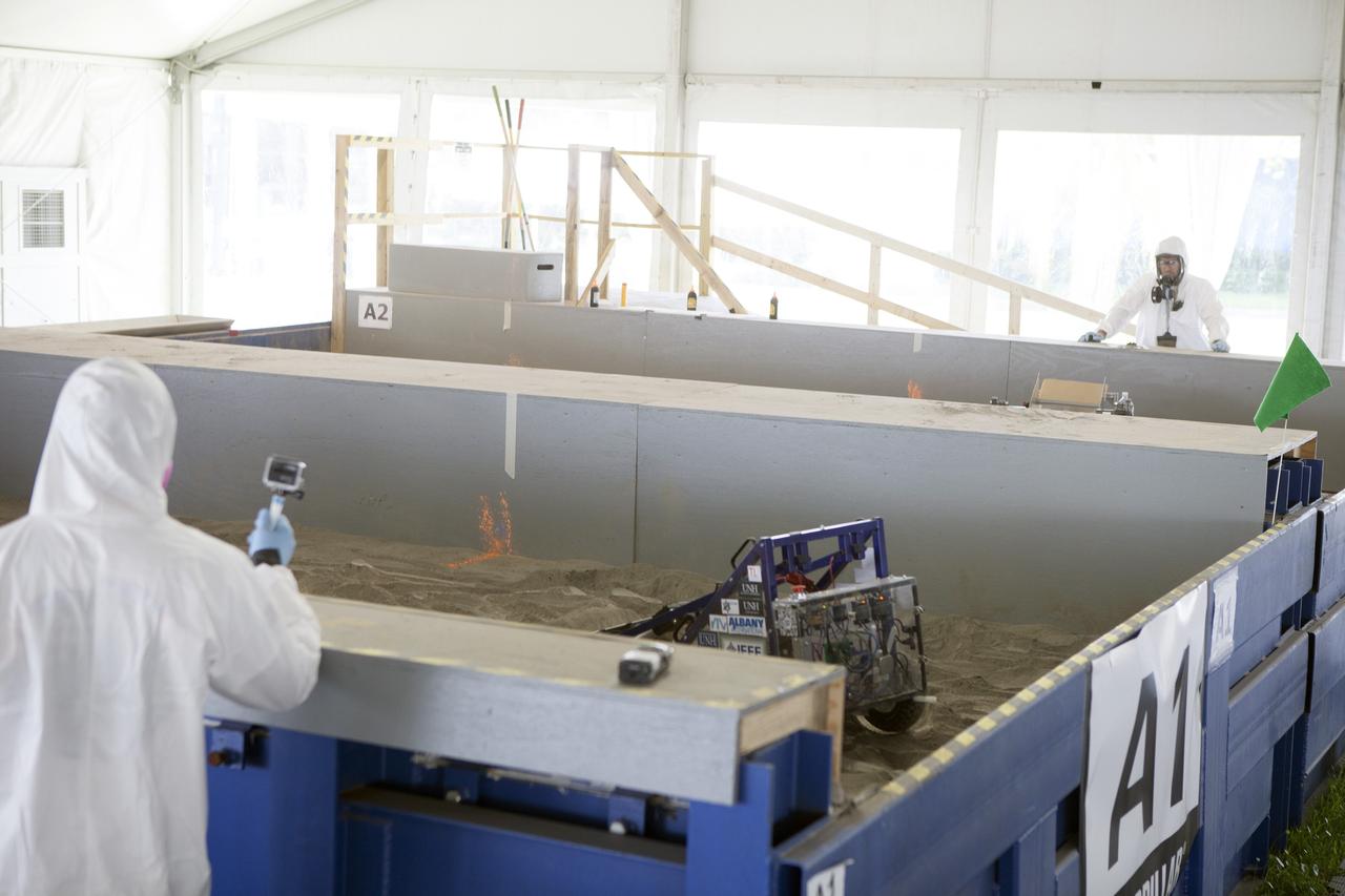 CAPE CANAVERAL, Fla. – Competition judges monitor two team's robots digging in the simulated Martian soil in the Caterpillar Mining Arena during NASA’s 2014 Robotic Mining Competition at the Kennedy Space Center Visitor Complex in Florida. More than 35 teams from colleges and universities around the U.S. have designed and built remote-controlled robots for the mining competition. The competition is a NASA Human Exploration and Operations Mission Directorate project designed to engage and retain students in science, technology, engineering and mathematics, or STEM, fields by expanding opportunities for student research and design. Teams use their remote-controlled robotics to maneuver and dig in a supersized sandbox filled with a crushed material that has characteristics similar to Martian soil. The objective of the challenge is to see which team’s robot can collect and move the most regolith within a specified amount of time. For more information, visit www.nasa.gov/nasarmc. Photo credit: NASA/Kim Shiflett