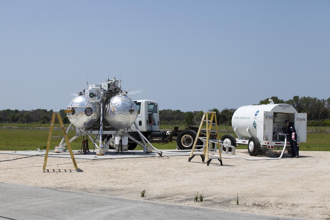 CAPE CANAVERAL, Fla. –NASA's Project Morpheus prototype lander is fueled prior to a free-flight test from a launch pad at the north end of the Shuttle Landing Facility at NASA’s Kennedy Space Center in Florida. Project Morpheus tests NASA’s ALHAT and an engine that runs on liquid oxygen and methane, which are green propellants. These new capabilities could be used in future efforts to deliver cargo to planetary surfaces. The landing facility provides the lander with the kind of field necessary for realistic testing, complete with rocks, craters and hazards to avoid. Morpheus’ ALHAT payload allows it to navigate to clear landing sites amidst rocks, craters and other hazards during its descent. Project Morpheus is being managed under the Advanced Exploration Systems, or AES, Division in NASA’s Human Exploration and Operations Mission Directorate. The efforts in AES pioneer new approaches for rapidly developing prototype systems, demonstrating key capabilities and validating operational concepts for future human missions beyond Earth orbit. For more information on Project Morpheus, visit http://morpheuslander.jsc.nasa.gov/. Photo credit: NASA/Kim Shiflett
