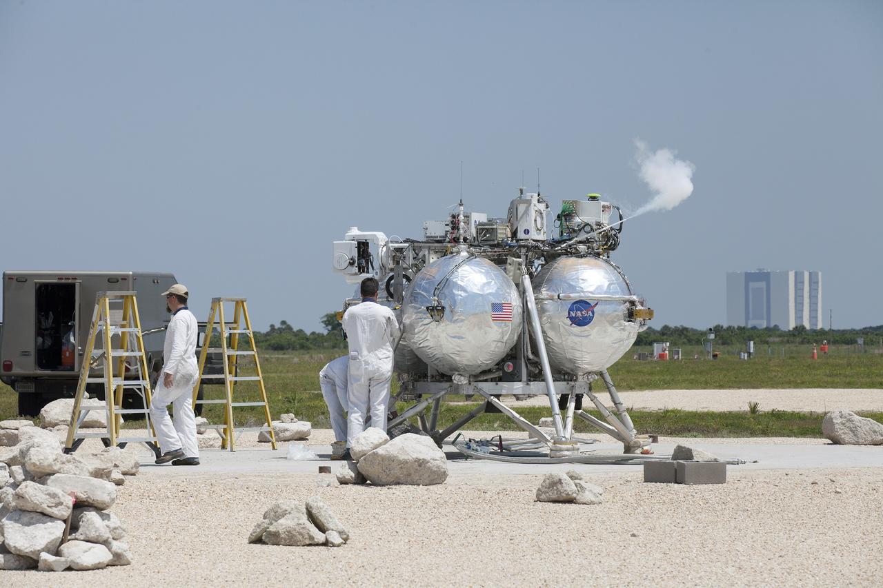 CAPE CANAVERAL, Fla. – At NASA's Kennedy Space Center in Florida, technicians check out the agency's Project Morpheus prototype lander which just touched down on a dedicated pad inside the ALHAT hazard field near the Shuttle Landing Facility. Project Morpheus tests NASA’s ALHAT and an engine that runs on liquid oxygen and methane, which are green propellants. These new capabilities could be used in future efforts to deliver cargo to planetary surfaces.      The landing facility provides the lander with the kind of field necessary for realistic testing, complete with rocks, craters and hazards to avoid. Morpheus’ ALHAT payload allows it to navigate to clear landing sites amidst rocks, craters and other hazards during its descent. Project Morpheus is being managed under the Advanced Exploration Systems, or AES, Division in NASA’s Human Exploration and Operations Mission Directorate. The efforts in AES pioneer new approaches for rapidly developing prototype systems, demonstrating key capabilities and validating operational concepts for future human missions beyond Earth orbit. For more information on Project Morpheus, visit http://morpheuslander.jsc.nasa.gov/. Photo credit: NASA/Kim Shiflett