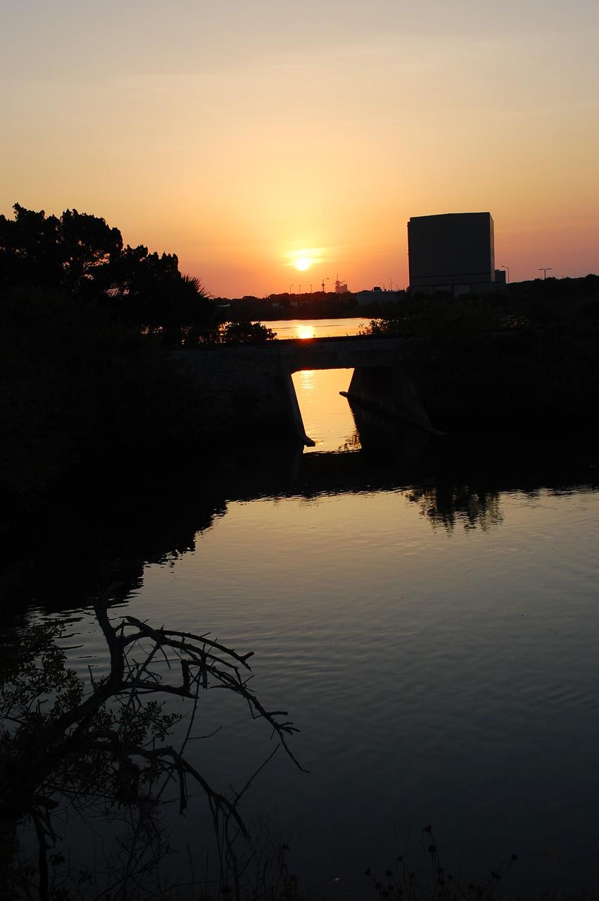 CAPE CANAVERAL, Fla. -- Sunrise is reflected in the water abundant on NASA's Kennedy Space Center in Florida. In the background are Launch Pad 39A and the Rotation/Processing Facility, which supported solid rocket booster preparations during the Space Shuttle Program. On this particular morning, preparations are underway for a launch from Space Launch Complex-41 on Cape Canaveral Air Force Station, a part of the spaceport which neighbors Kennedy Space Center. For more information, visit http://www.nasa.gov/centers/kennedy. Photo credit: NASA/Ben Smegelsky