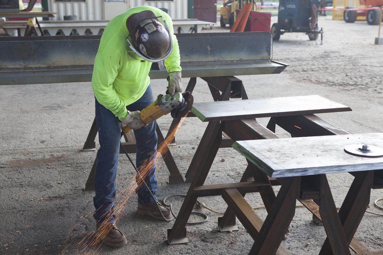 CAPE CANAVERAL, Fla. -- Modifications continue on the Mobile Launcher, or ML, at the Mobile Launcher Park Site at NASA’s Kennedy Space Center in Florida. A construction worker trims a section of a steel wall. The ML is being modified and strengthened to accommodate the weight, size and thrust at launch of NASA's Space Launch System, or SLS, and Orion spacecraft.    In 2013, the agency awarded a contract to J.P. Donovan Construction Inc. of Rockledge, Fla., to modify the ML, which is one of the key elements of ground support equipment that is being upgraded by the Ground Systems Development and Operations Program office at Kennedy. The existing 24-foot exhaust hole is being enlarged and strengthened for the larger, heavier SLS rocket. The ML will carry the SLS rocket and Orion spacecraft to Launch Pad 39B for its first mission, Exploration Mission-1, in 2017. Photo credit: NASA/Daniel Casper