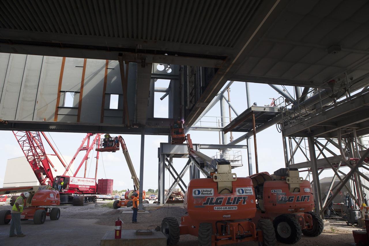 CAPE CANAVERAL, Fla. -- Construction workers on lifts continue modifications underneath the Mobile Launcher, or ML, at the Mobile Launcher Park Site at NASA’s Kennedy Space Center in Florida. Sections of the ML are being modified and strengthened to accommodate the weight, size and thrust at launch of NASA's Space Launch System and Orion spacecraft.    In 2013, the agency awarded a contract to J.P. Donovan Construction Inc. of Rockledge, Fla., to modify the ML, which is one of the key elements of ground support equipment that is being upgraded by the Ground Systems Development and Operations Program office at Kennedy. The existing 24-foot exhaust hole is being enlarged and strengthened for the larger, heavier SLS rocket. The ML will carry the SLS rocket and Orion spacecraft to Launch Pad 39B for its first mission, Exploration Mission-1, in 2017. Photo credit: NASA/Daniel Casper