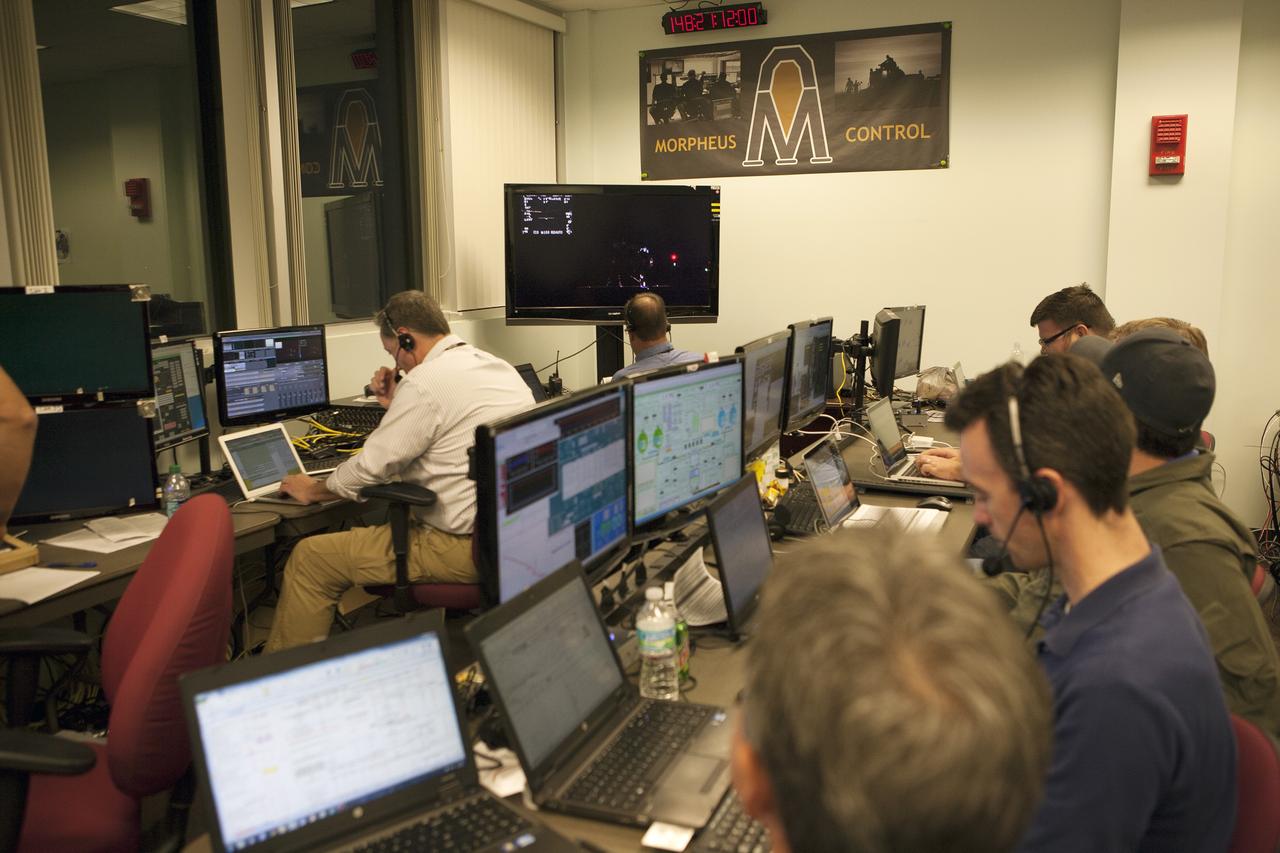 CAPE CANAVERAL, Fla. -- Engineers in the Morpheus Control Room monitor conditions in preparation for the first free flight test at night of NASA's Project Morpheus prototype lander from a launch pad at the north end of the Shuttle Landing Facility at NASA's Kennedy Space Center in Florida. The 98-second test began at 10:02 p.m. EDT with the Morpheus lander launching from the ground over a flame trench and ascending more than 800 feet. The vehicle, with its autonomous landing and hazard avoidance technology, or ALHAT sensors, surveyed the hazard field to determine safe landing sites. Morpheus then flew forward and downward covering approximately 1,300 feet while performing a 78-foot divert to simulate a hazard avoidance maneuver. The lander then descended and landed on a dedicated pad inside the test field. Project Morpheus tests NASA’s ALHAT and an engine that runs on liquid oxygen and methane, which are green propellants. These new capabilities could be used in future efforts to deliver cargo to planetary surfaces.    The landing facility provides the lander with the kind of field necessary for realistic testing, complete with rocks, craters and hazards to avoid. Morpheus’ ALHAT payload allows it to navigate to clear landing sites amidst rocks, craters and other hazards during its descent. Project Morpheus is being managed under the Advanced Exploration Systems, or AES, Division in NASA’s Human Exploration and Operations Mission Directorate. The efforts in AES pioneer new approaches for rapidly developing prototype systems, demonstrating key capabilities and validating operational concepts for future human missions beyond Earth orbit. For more information on Project Morpheus, visit http://morpheuslander.jsc.nasa.gov/.  Photo credit: NASA/Kim Shiflett