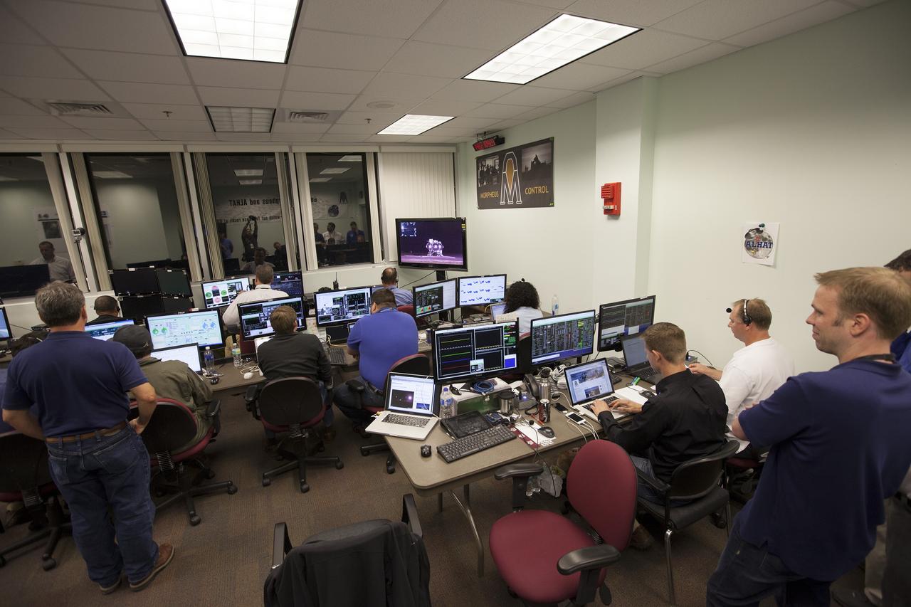 CAPE CANAVERAL, Fla. -- Engineers in the Morpheus Control Room monitor conditions in preparation for the first free flight test at night of NASA's Project Morpheus prototype lander from a launch pad at the north end of the Shuttle Landing Facility at NASA's Kennedy Space Center in Florida. The 98-second test began at 10:02 p.m. EDT with the Morpheus lander launching from the ground over a flame trench and ascending more than 800 feet. The vehicle, with its autonomous landing and hazard avoidance technology, or ALHAT sensors, surveyed the hazard field to determine safe landing sites. Morpheus then flew forward and downward covering approximately 1,300 feet while performing a 78-foot divert to simulate a hazard avoidance maneuver. The lander then descended and landed on a dedicated pad inside the test field. Project Morpheus tests NASA’s ALHAT and an engine that runs on liquid oxygen and methane, which are green propellants. These new capabilities could be used in future efforts to deliver cargo to planetary surfaces. The landing facility provides the lander with the kind of field necessary for realistic testing, complete with rocks, craters and hazards to avoid. Morpheus’ ALHAT payload allows it to navigate to clear landing sites amidst rocks, craters and other hazards during its descent. Project Morpheus is being managed under the Advanced Exploration Systems, or AES, Division in NASA’s Human Exploration and Operations Mission Directorate. The efforts in AES pioneer new approaches for rapidly developing prototype systems, demonstrating key capabilities and validating operational concepts for future human missions beyond Earth orbit. For more information on Project Morpheus, visit http://morpheuslander.jsc.nasa.gov/. Photo credit: NASA/Kim Shiflett