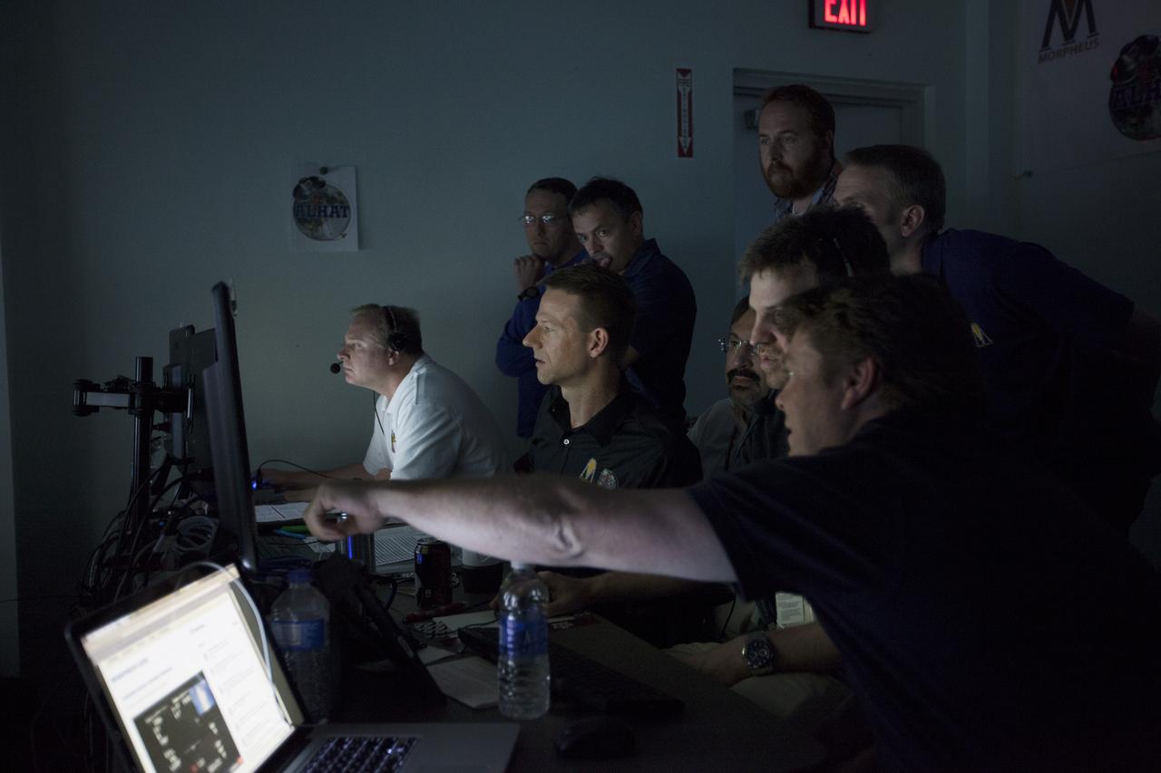 CAPE CANAVERAL, Fla. -- Engineers in the Morpheus Control Room monitor NASA's Project Morpheus prototype lander as it soars high on the first free flight test at night from a launch pad at the north end of the Shuttle Landing Facility at NASA's Kennedy Space Center in Florida. The 98-second test began at 10:02 p.m. EDT with the Morpheus lander launching from the ground over a flame trench and ascending more than 800 feet. The vehicle, with its autonomous landing and hazard avoidance technology, or ALHAT sensors, surveyed the hazard field to determine safe landing sites. Morpheus then flew forward and downward covering approximately 1,300 feet while performing a 78-foot divert to simulate a hazard avoidance maneuver. The lander then descended and landed on a dedicated pad inside the test field. Project Morpheus tests NASA’s ALHAT and an engine that runs on liquid oxygen and methane, which are green propellants. These new capabilities could be used in future efforts to deliver cargo to planetary surfaces.    The landing facility provides the lander with the kind of field necessary for realistic testing, complete with rocks, craters and hazards to avoid. Morpheus’ ALHAT payload allows it to navigate to clear landing sites amidst rocks, craters and other hazards during its descent. Project Morpheus is being managed under the Advanced Exploration Systems, or AES, Division in NASA’s Human Exploration and Operations Mission Directorate. The efforts in AES pioneer new approaches for rapidly developing prototype systems, demonstrating key capabilities and validating operational concepts for future human missions beyond Earth orbit. For more information on Project Morpheus, visit http://morpheuslander.jsc.nasa.gov/.  Photo credit: NASA/Kim Shiflett
