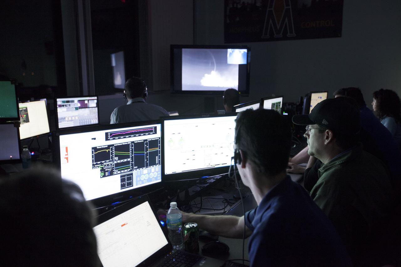 CAPE CANAVERAL, Fla. -- Engineers in the Morpheus Control Room monitor NASA's Project Morpheus prototype lander as it soars high on the first free flight test at night from a launch pad at the north end of the Shuttle Landing Facility at NASA's Kennedy Space Center in Florida. The 98-second test began at 10:02 p.m. EDT with the Morpheus lander launching from the ground over a flame trench and ascending more than 800 feet. The vehicle, with its autonomous landing and hazard avoidance technology, or ALHAT sensors, surveyed the hazard field to determine safe landing sites. Morpheus then flew forward and downward covering approximately 1,300 feet while performing a 78-foot divert to simulate a hazard avoidance maneuver. The lander then descended and landed on a dedicated pad inside the test field. Project Morpheus tests NASA’s ALHAT and an engine that runs on liquid oxygen and methane, which are green propellants. These new capabilities could be used in future efforts to deliver cargo to planetary surfaces.    The landing facility provides the lander with the kind of field necessary for realistic testing, complete with rocks, craters and hazards to avoid. Morpheus’ ALHAT payload allows it to navigate to clear landing sites amidst rocks, craters and other hazards during its descent. Project Morpheus is being managed under the Advanced Exploration Systems, or AES, Division in NASA’s Human Exploration and Operations Mission Directorate. The efforts in AES pioneer new approaches for rapidly developing prototype systems, demonstrating key capabilities and validating operational concepts for future human missions beyond Earth orbit. For more information on Project Morpheus, visit http://morpheuslander.jsc.nasa.gov/.  Photo credit: NASA/Kim Shiflett