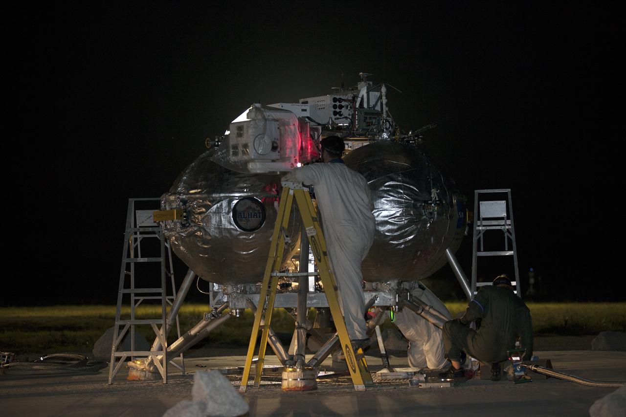 CAPE CANAVERAL, Fla. -- Technicians perform safing procedures on NASA's Project Morpheus prototype lander after completing the first free flight test at night from a launch pad at the north end of the Shuttle Landing Facility at NASA's Kennedy Space Center in Florida. The 98-second test began at 10:02 p.m. EDT with the Morpheus lander launching from the ground over a flame trench and ascending more than 800 feet. The vehicle, with its autonomous landing and hazard avoidance technology, or ALHAT sensors, surveyed the hazard field to determine safe landing sites. Morpheus then flew forward and downward covering approximately 1,300 feet while performing a 78-foot divert to simulate a hazard avoidance maneuver. The lander then descended and landed on a dedicated pad inside the test field. Project Morpheus tests NASA’s ALHAT and an engine that runs on liquid oxygen and methane, which are green propellants. These new capabilities could be used in future efforts to deliver cargo to planetary surfaces. The landing facility provides the lander with the kind of field necessary for realistic testing, complete with rocks, craters and hazards to avoid. Morpheus’ ALHAT payload allows it to navigate to clear landing sites amidst rocks, craters and other hazards during its descent. Project Morpheus is being managed under the Advanced Exploration Systems, or AES, Division in NASA’s Human Exploration and Operations Mission Directorate. The efforts in AES pioneer new approaches for rapidly developing prototype systems, demonstrating key capabilities and validating operational concepts for future human missions beyond Earth orbit. For more information on Project Morpheus, visit http://morpheuslander.jsc.nasa.gov/. Photo credit: NASA/Kim Shiflett