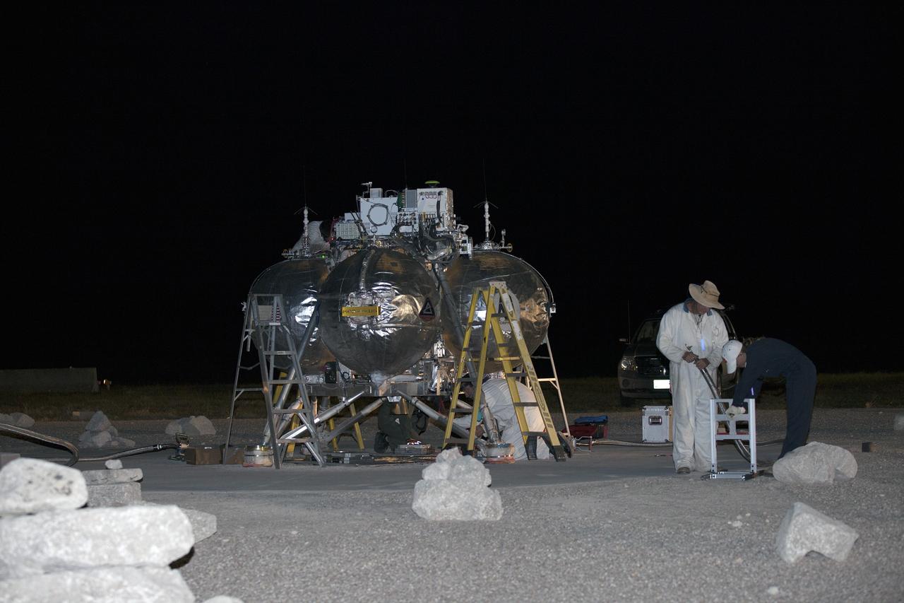 CAPE CANAVERAL, Fla. -- Technicians perform safing procedures on NASA's Project Morpheus prototype lander after completing the first free flight test at night from a launch pad at the north end of the Shuttle Landing Facility at NASA's Kennedy Space Center in Florida. The 98-second test began at 10:02 p.m. EDT with the Morpheus lander launching from the ground over a flame trench and ascending more than 800 feet. The vehicle, with its autonomous landing and hazard avoidance technology, or ALHAT sensors, surveyed the hazard field to determine safe landing sites. Morpheus then flew forward and downward covering approximately 1,300 feet while performing a 78-foot divert to simulate a hazard avoidance maneuver. The lander then descended and landed on a dedicated pad inside the test field. Project Morpheus tests NASA’s ALHAT and an engine that runs on liquid oxygen and methane, which are green propellants. These new capabilities could be used in future efforts to deliver cargo to planetary surfaces. The landing facility provides the lander with the kind of field necessary for realistic testing, complete with rocks, craters and hazards to avoid. Morpheus’ ALHAT payload allows it to navigate to clear landing sites amidst rocks, craters and other hazards during its descent. Project Morpheus is being managed under the Advanced Exploration Systems, or AES, Division in NASA’s Human Exploration and Operations Mission Directorate. The efforts in AES pioneer new approaches for rapidly developing prototype systems, demonstrating key capabilities and validating operational concepts for future human missions beyond Earth orbit. For more information on Project Morpheus, visit http://morpheuslander.jsc.nasa.gov/. Photo credit: NASA/Kim Shiflett