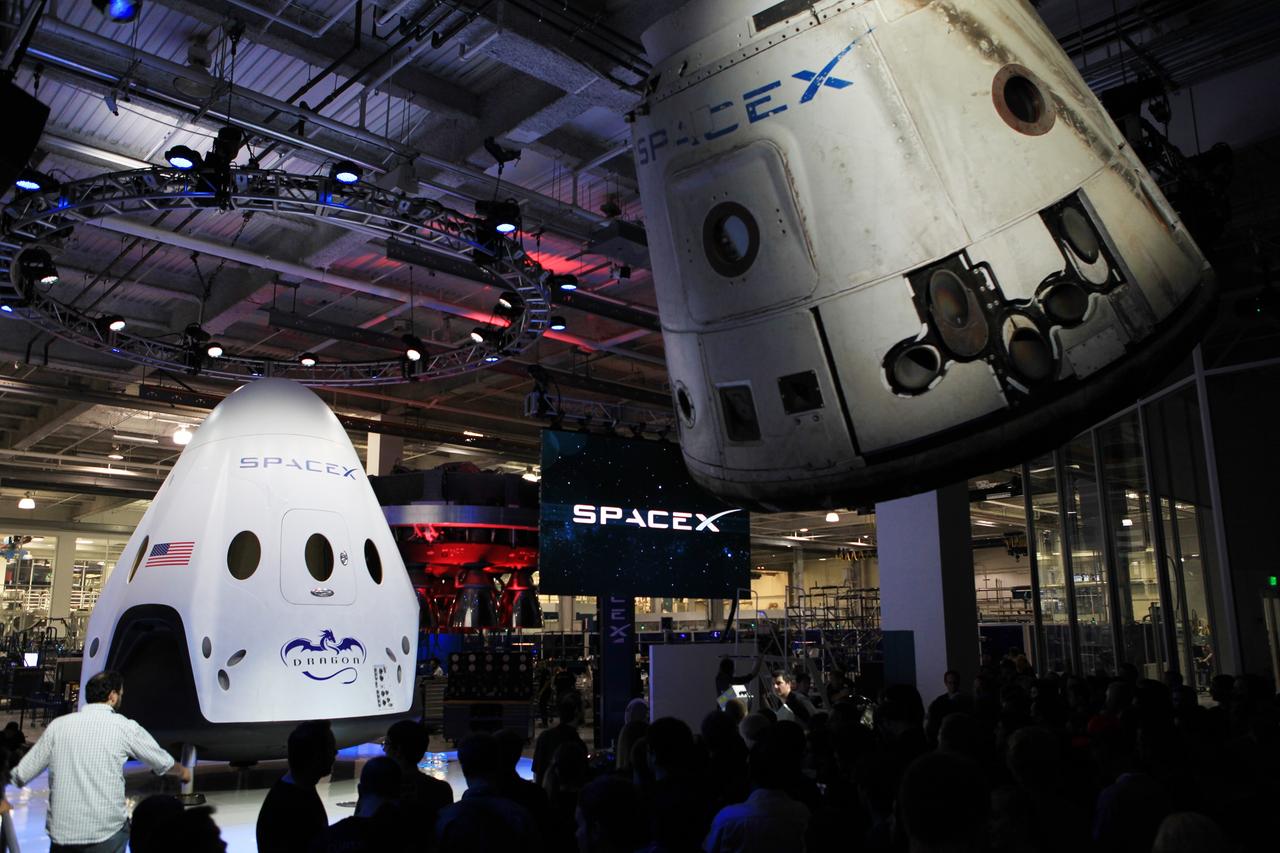 HAWTHORNE, Calif. - The Dragon V2 stands on a stage inside SpaceX headquarters in Hawthorne, Calif., near a suspended cargo-carrying Dragon spacecraft that flew a previous mission. The new spacecraft, the Dragon V2, is designed to carry people into Earth's orbit and was developed in partnership with NASA's Commercial Crew Program under the Commercial Crew Integrated Capability agreement. SpaceX is one of NASA's commercial partners working to develop a new generation of U.S. spacecraft and rockets capable of transporting humans to and from Earth's orbit from American soil. Ultimately, NASA intends to use such commercial systems to fly U.S. astronauts to and from the International Space Station. Photo credit: NASA/Dimitri Gerondidakis
