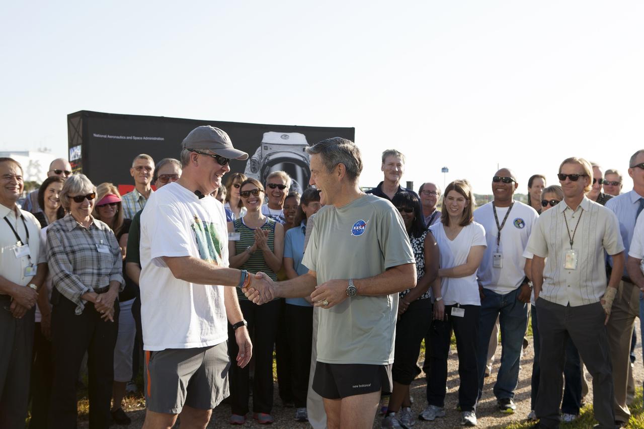 CAPE CANAVERAL, Fla. – Kennedy Space Center Director Bob Cabana, right, shakes hands with Florida State Surgeon General John Armstrong before an early morning run along the center's Pathfinder Trail near the Operations and Support Building II at Kennedy Space Center in Florida, to officially kick off National Employee Health and Fitness Month with the NASA Moves! challenge.    NASA Moves! challenged the workforce from each of the agency's field centers to engage in at least 20 minutes of activity, or 10,000 steps, each day from May 18-31. About 100 people participated in the kickoff event on the Pathfinder Trail in the heart of the center's Launch Complex 39. The one-third-mile-long gravel walkway traces the iconic shape of a space shuttle orbiter and features a set of exercise stations. The friendly contest is part of NASA's new Health4Life initiative, a Web-based health initiative designed to help employees track their health, fitness and nutrition. Health4Life also provides an array of resources geared toward increasing physical activity. Photo credit: NASA/Dimitri Gerondidakis