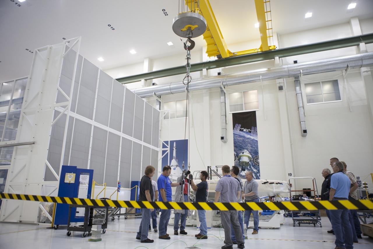CAPE CANAVERAL, Fla. -- Lockheed Martin technicians attach a crane to the Orion heat shield to prepare to move it away from a stand inside the Operations and Checkout Building high bay at NASA's Kennedy Space Center in Florida. Technicians have installed more than 200 instrumentation sensors on the heat shield and are preparing it for installation on the Orion crew module.    Orion is the exploration spacecraft designed to carry astronauts to destinations not yet explored by humans, including an asteroid and Mars. It will have emergency abort capability, sustain the crew during space travel and provide safe re-entry from deep space return velocities. The first unpiloted test flight of the Orion is scheduled to launch later this year atop a Delta IV rocket from Cape Canaveral Air Force Station in Florida to an altitude of 3,600 miles above the Earth's surface. The two-orbit, four-hour flight test will help engineers evaluate the systems critical to crew safety including the heat shield, parachute system and launch abort system. For more information, visit http://www.nasa.gov/orion. Photo credit: NASA/Frankie Martin