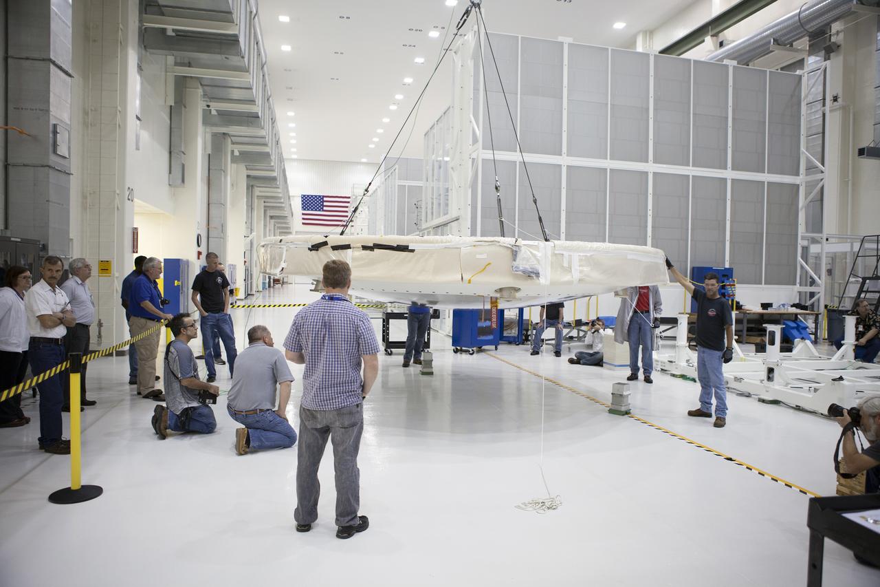 CAPE CANAVERAL, Fla. -- Inside the Operations and Checkout Building high bay at NASA's Kennedy Space Center in Florida, Lockheed Martin technicians and engineers monitor the progress as a crane positions the Orion heat shield near the crew module in the high bay. Technicians have installed more than 200 instrumentation sensors on the heat shield and are preparing it for installation on the Orion crew module.     Orion is the exploration spacecraft designed to carry astronauts to destinations not yet explored by humans, including an asteroid and Mars. It will have emergency abort capability, sustain the crew during space travel and provide safe re-entry from deep space return velocities. The first unpiloted test flight of the Orion is scheduled to launch later this year atop a Delta IV rocket from Cape Canaveral Air Force Station in Florida to an altitude of 3,600 miles above the Earth's surface. The two-orbit, four-hour flight test will help engineers evaluate the systems critical to crew safety including the heat shield, parachute system and launch abort system. For more information, visit http://www.nasa.gov/orion. Photo credit: NASA/Frankie Martin