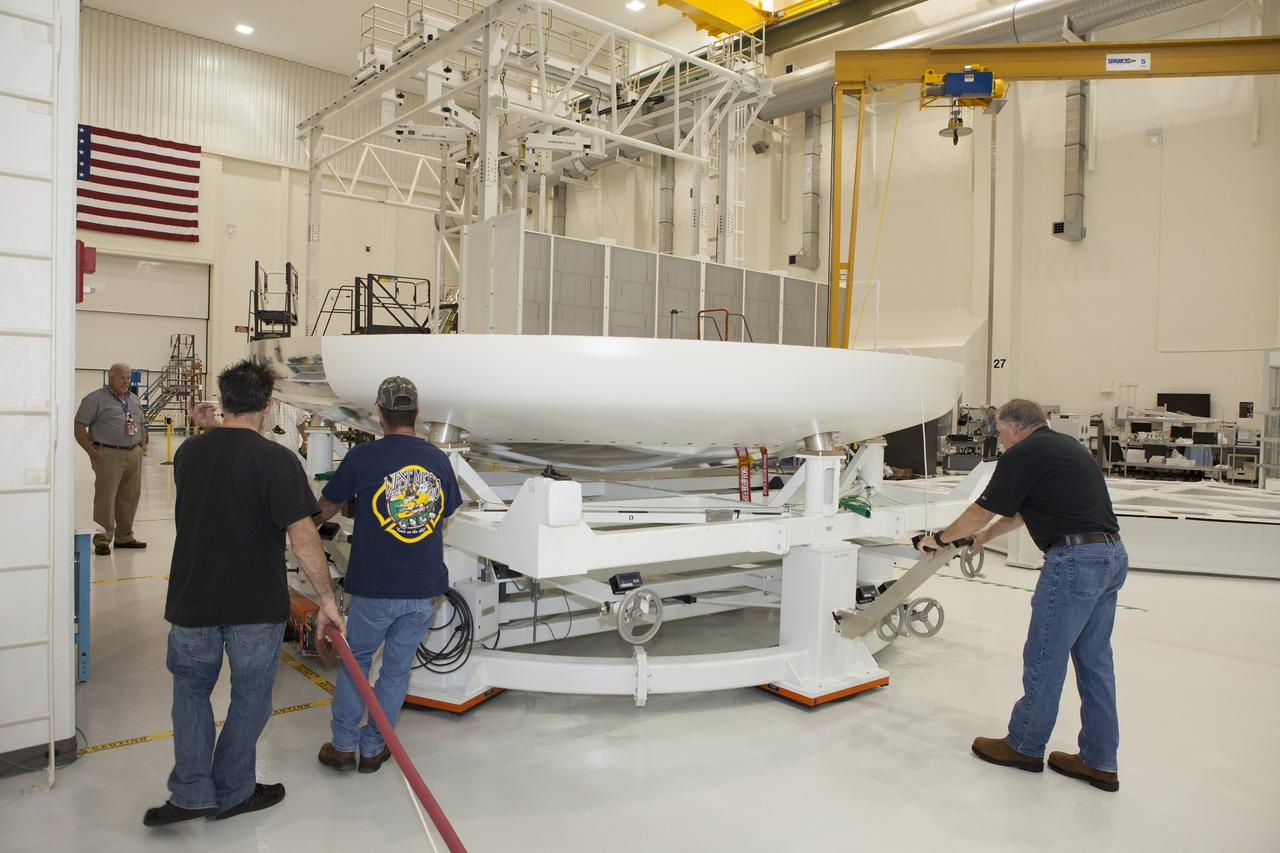 CAPE CANAVERAL, Fla. -- Lockheed Martin technicians and engineers move the heat shield for the Orion crew module down the aisle inside the Operations and Checkout Building high bay at NASA's Kennedy Space Center in Florida. Technicians have installed more than 200 instrumentation sensors on the heat shield and are preparing it for installation on the crew module.    Orion is the exploration spacecraft designed to carry astronauts to destinations not yet explored by humans, including an asteroid and Mars. It will have emergency abort capability, sustain the crew during space travel and provide safe re-entry from deep space return velocities. The first unpiloted test flight of the Orion is scheduled to launch later this year atop a Delta IV rocket from Cape Canaveral Air Force Station in Florida to an altitude of 3,600 miles above the Earth's surface. The two-orbit, four-hour flight test will help engineers evaluate the systems critical to crew safety including the heat shield, parachute system and launch abort system. For more information, visit http://www.nasa.gov/orion. Photo credit: NASA/Daniel Casper